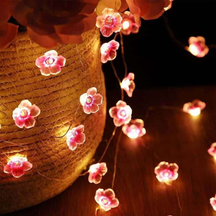 A Vase With Pink Flowers And Lights Background