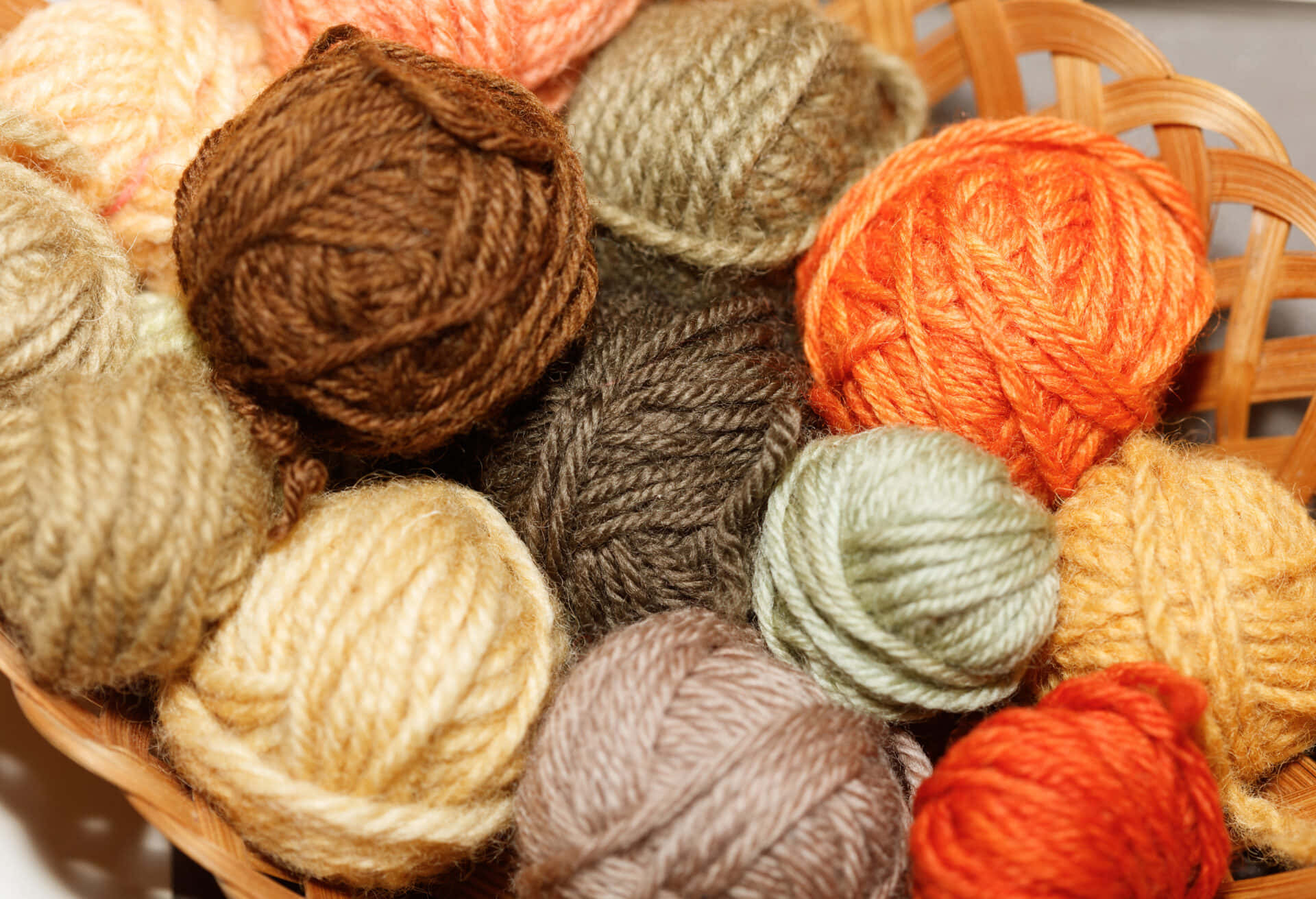 A Vibrant Basketful Of Multicolored Knitting Yarns Background