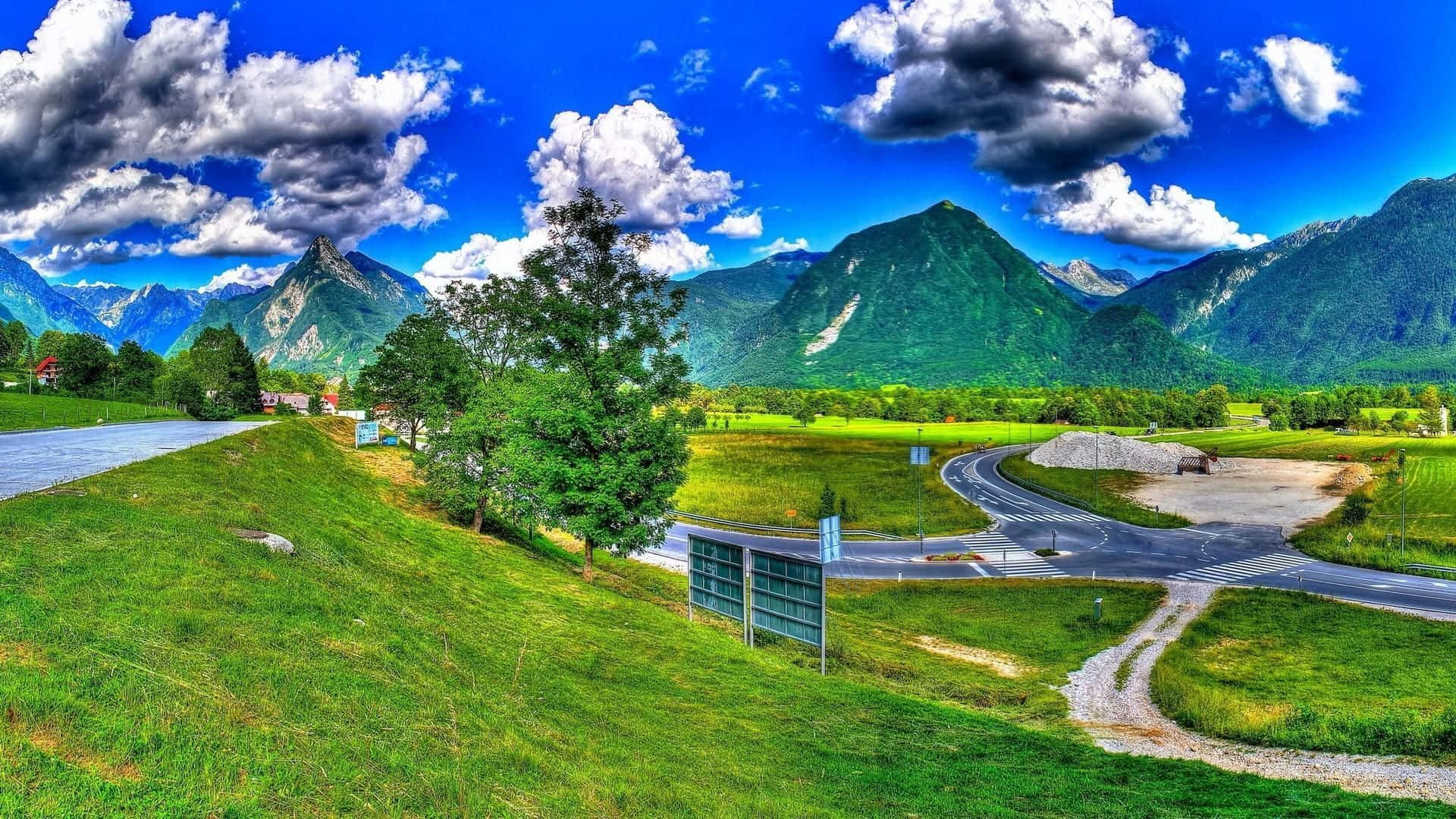 A View Of A Mountain Road And A Green Field Background