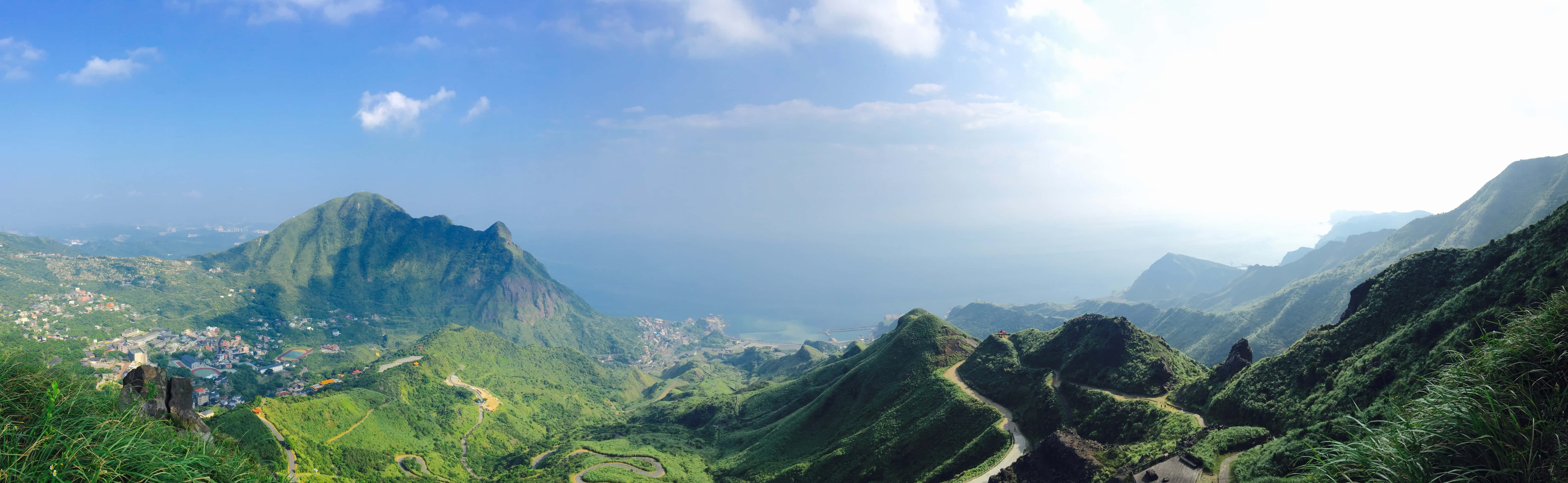 A View Of A Mountain With Green Grass And Mountains