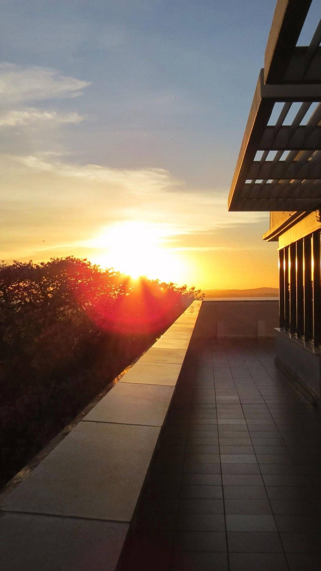 A View Of The Sun Setting Over A Rooftop Background