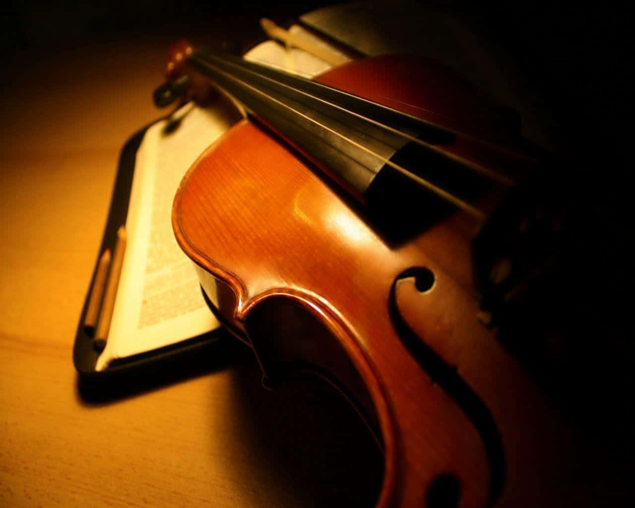 A Violin Is Sitting On A Table With An Open Book Background