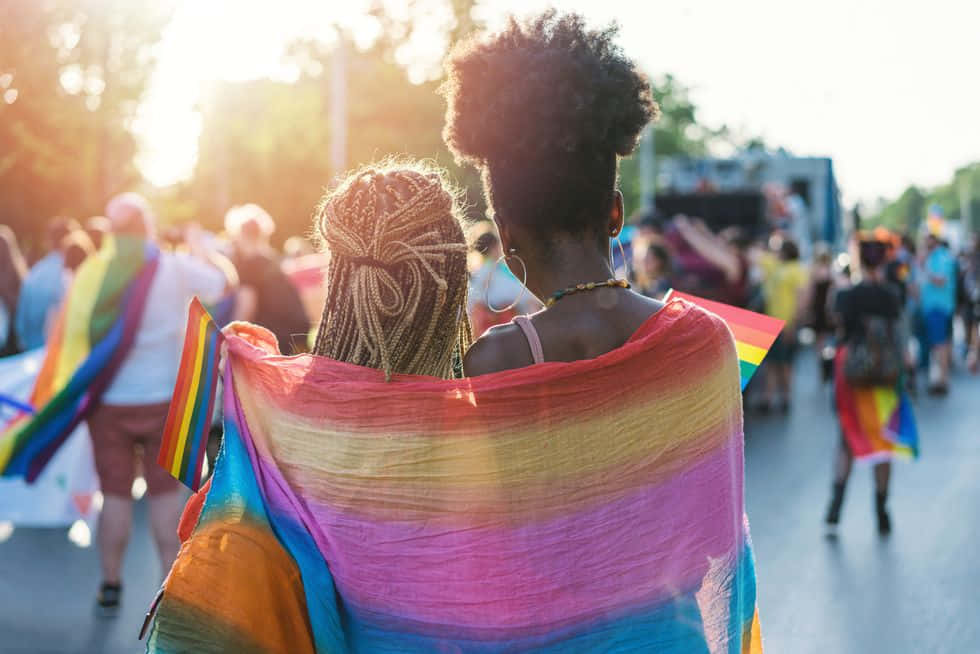A Warm, Inspiring Image Of A Lesbian Couple Under A Cute Lgbt Flag. Background