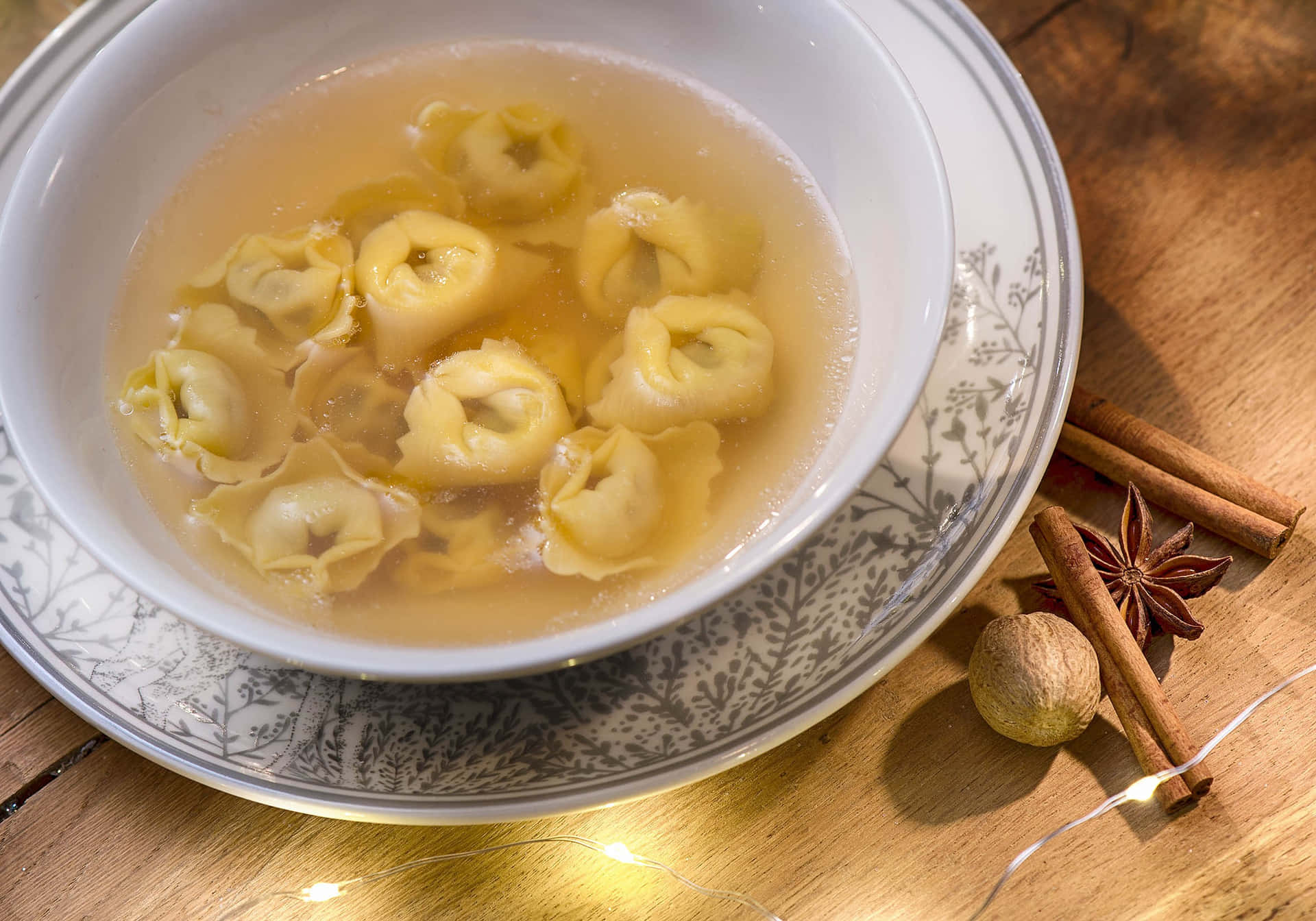 A Warm Serving Of Traditional Tortellini In Brodo With Cinnamon Rolls Background