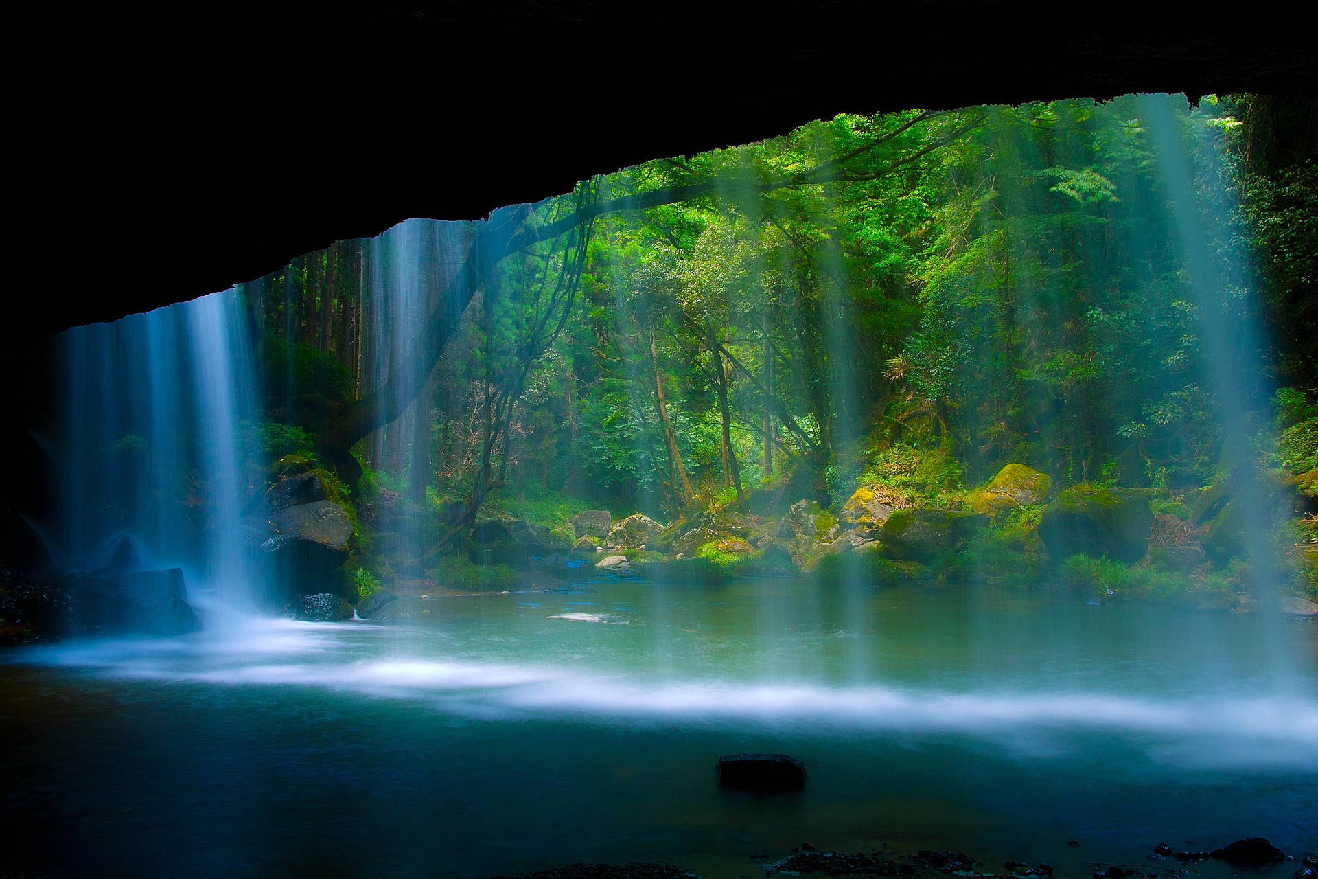 A Waterfall Is Flowing Through A Cave Background