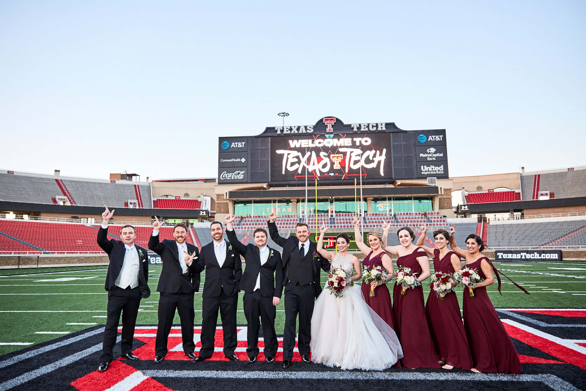 A Wedding Party Poses For A Photo On A Football Field Background