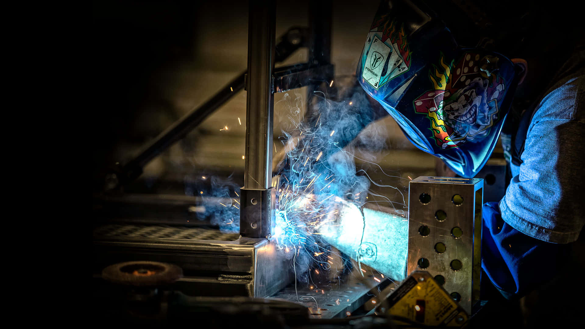 A Welder Is Welding Metal In A Dark Room Background