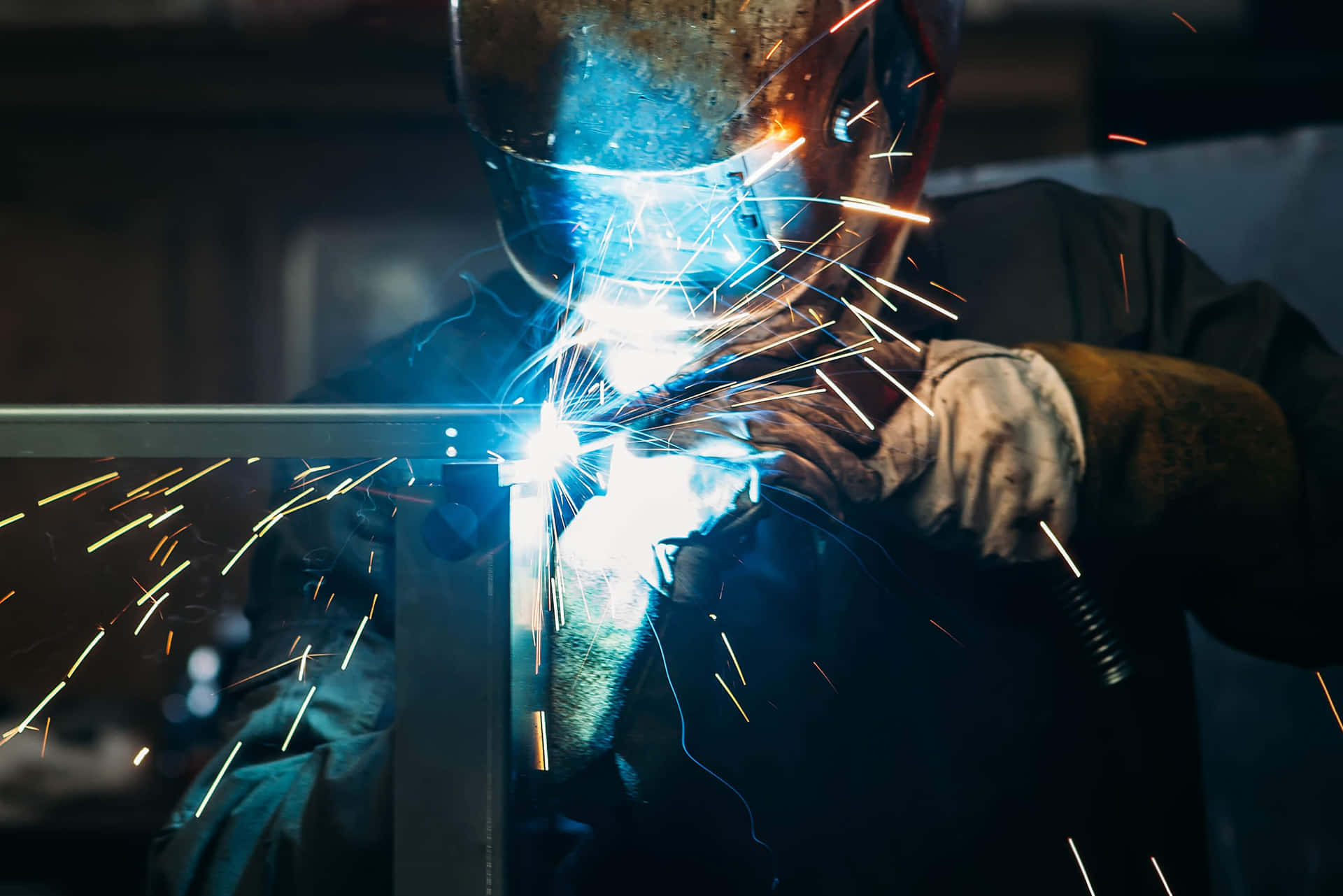 A Welder Is Welding Metal In A Factory Background