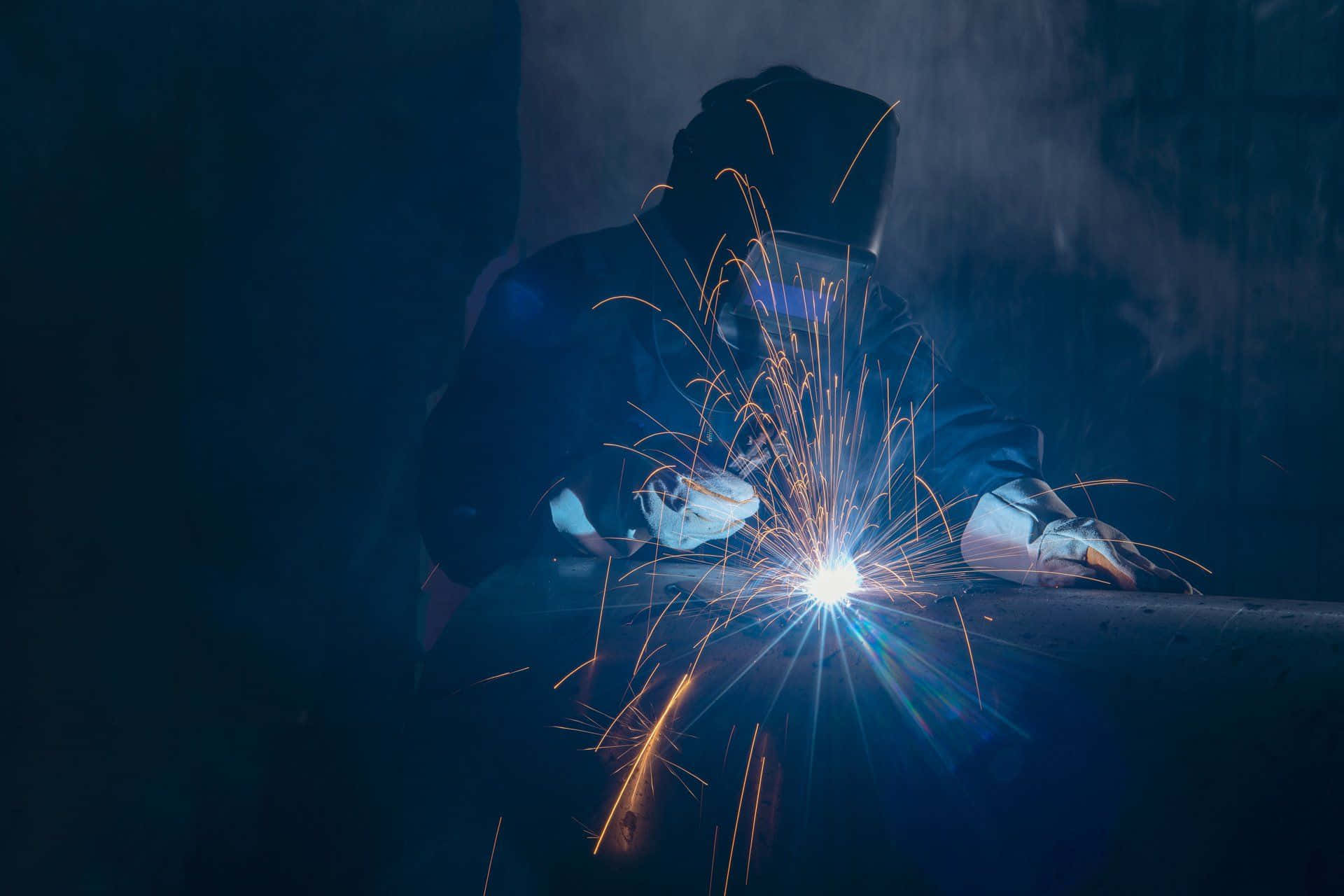 A Welder Is Working On A Metal Piece Background