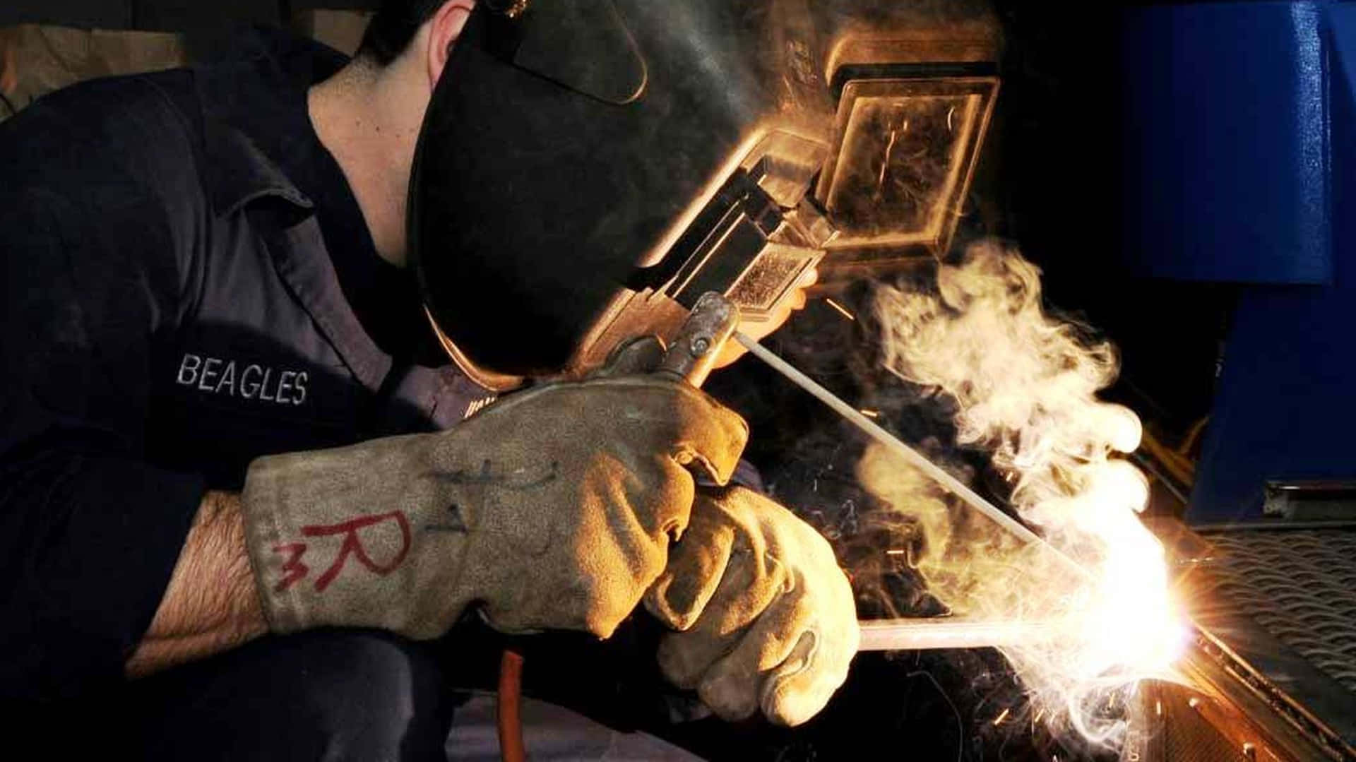 A Welder Perfectly Joining Two Pieces Of Stainless Steel Background