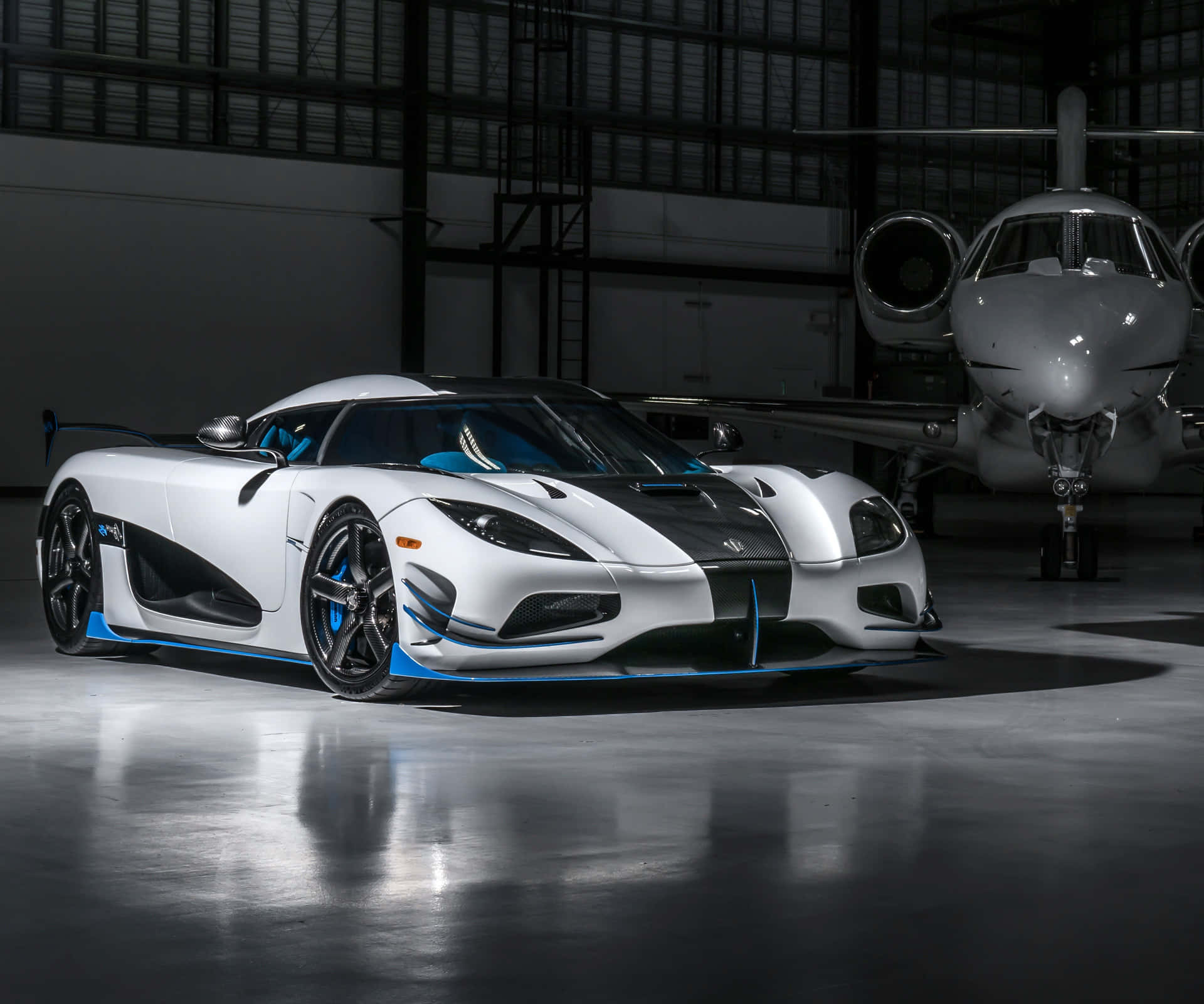 A White And Blue Sports Car Is Parked In Front Of A Plane Background