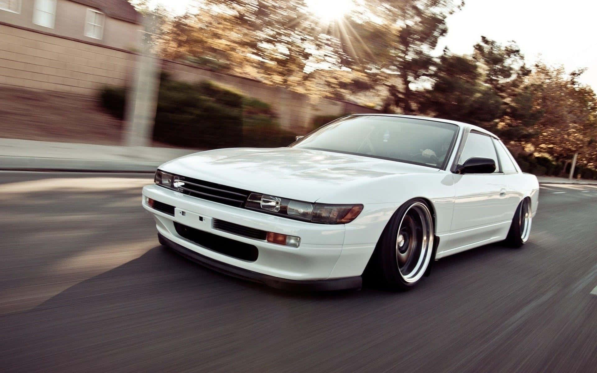 A White Car Driving Down The Street Background