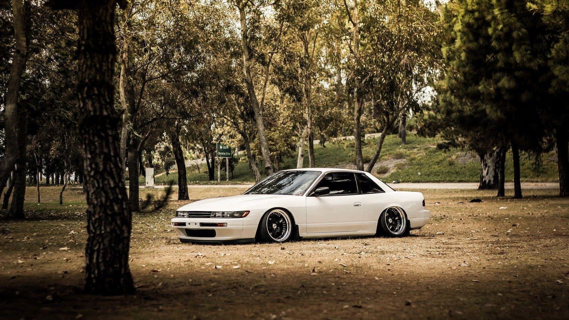 A White Car Parked In The Middle Of A Park Background