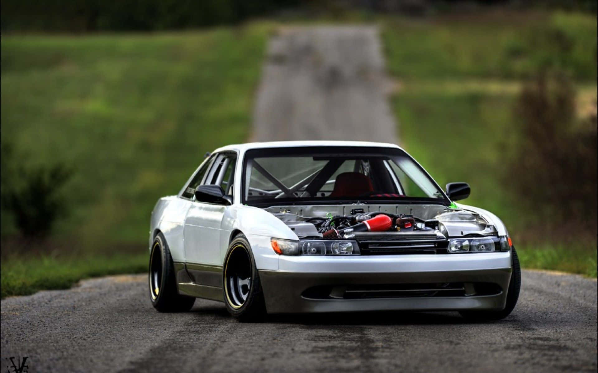 A White Car With A Red Hood On A Road Background