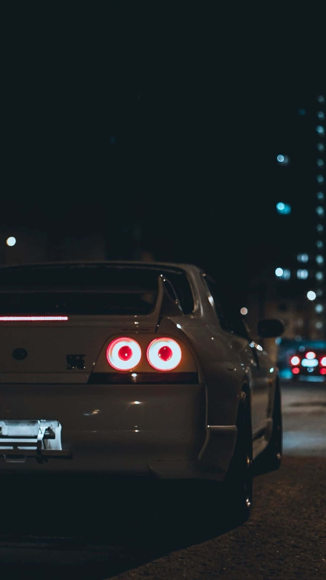 A White Car With Red Lights On The Road At Night