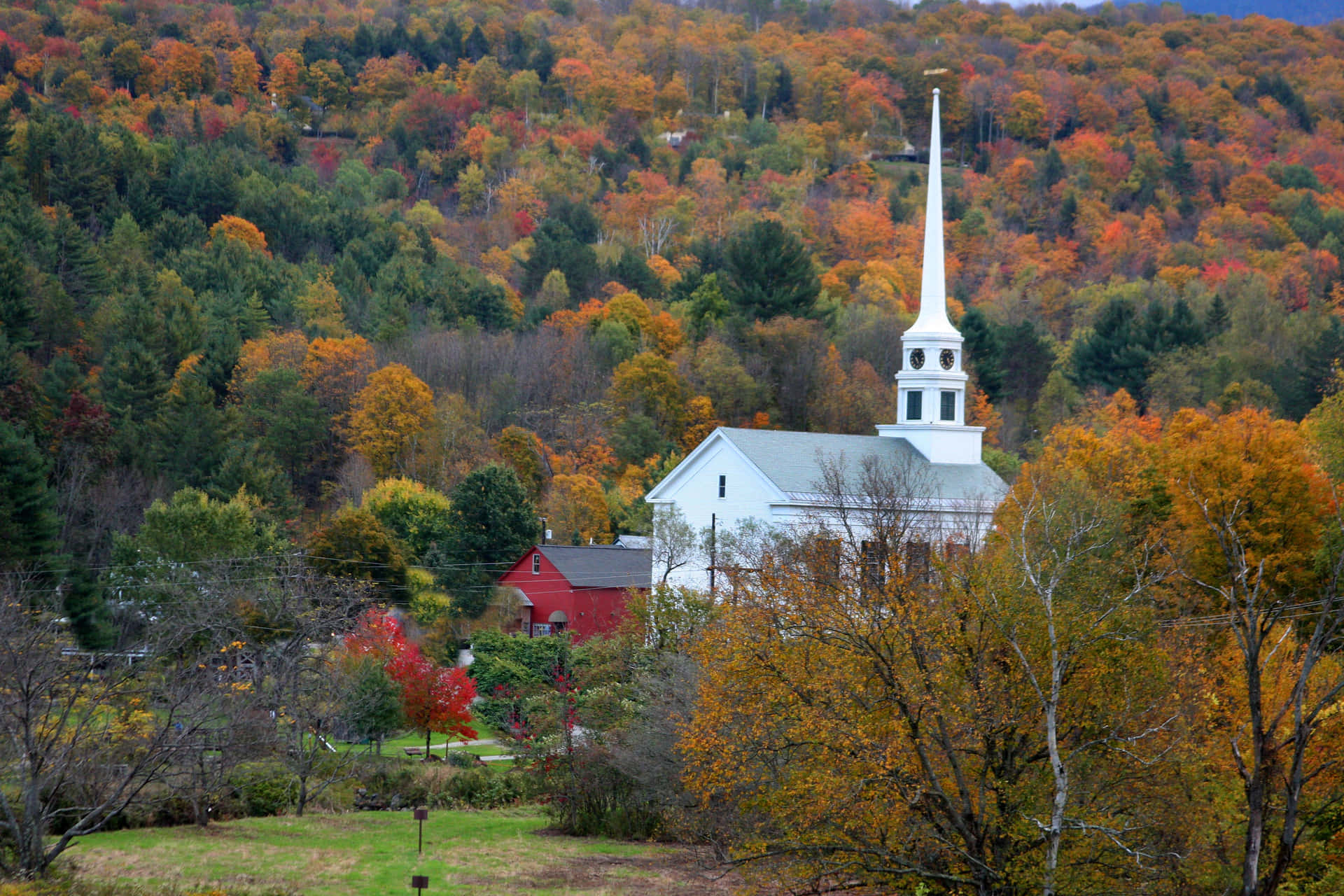 A White Church Surrounded By Fall Foliage Background