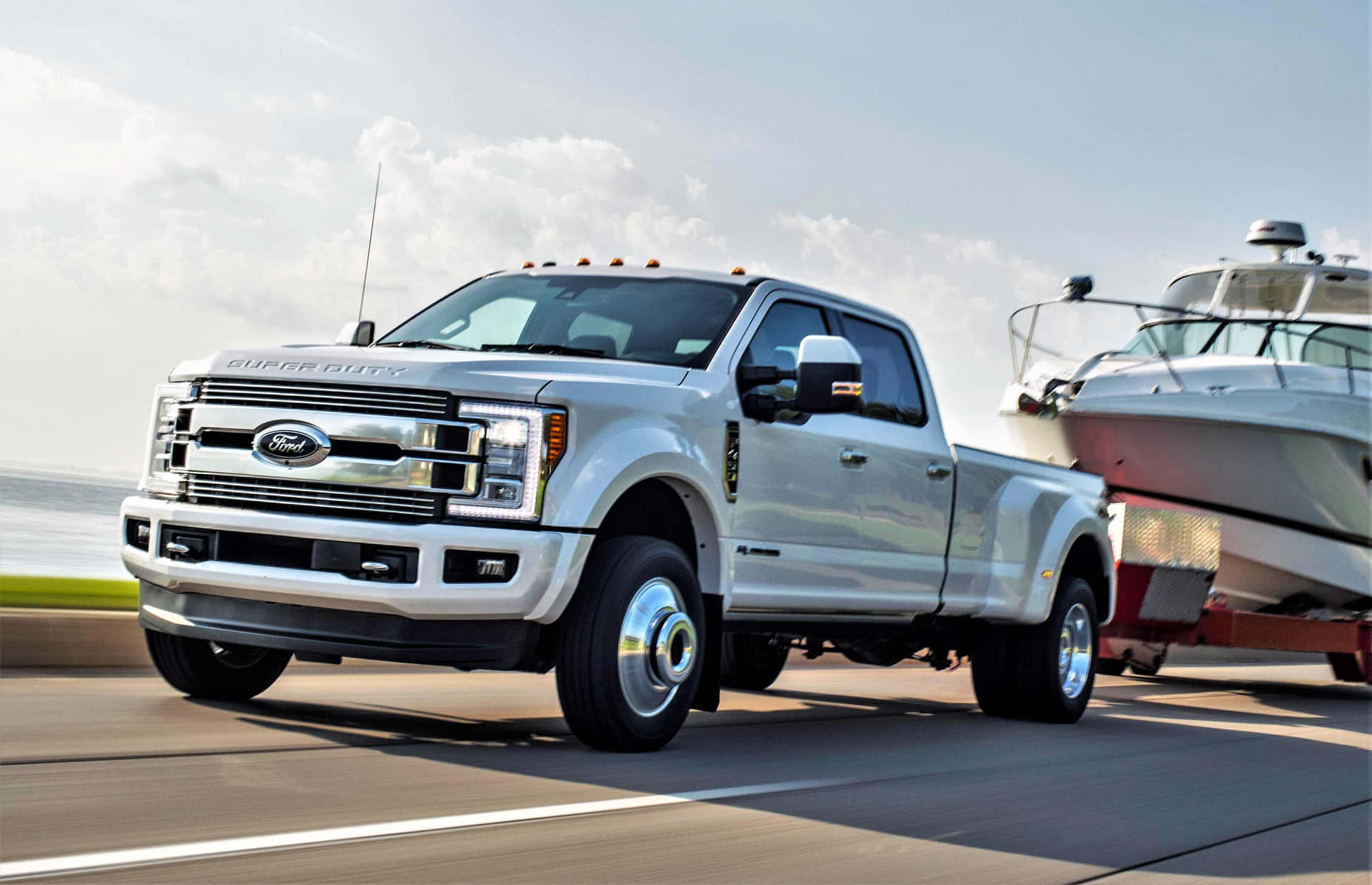 A White Ford Super Duty Truck Is Towing A Boat Background