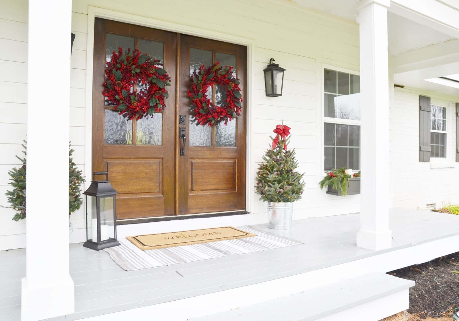 A White Front Porch With Wreaths And Potted Plants