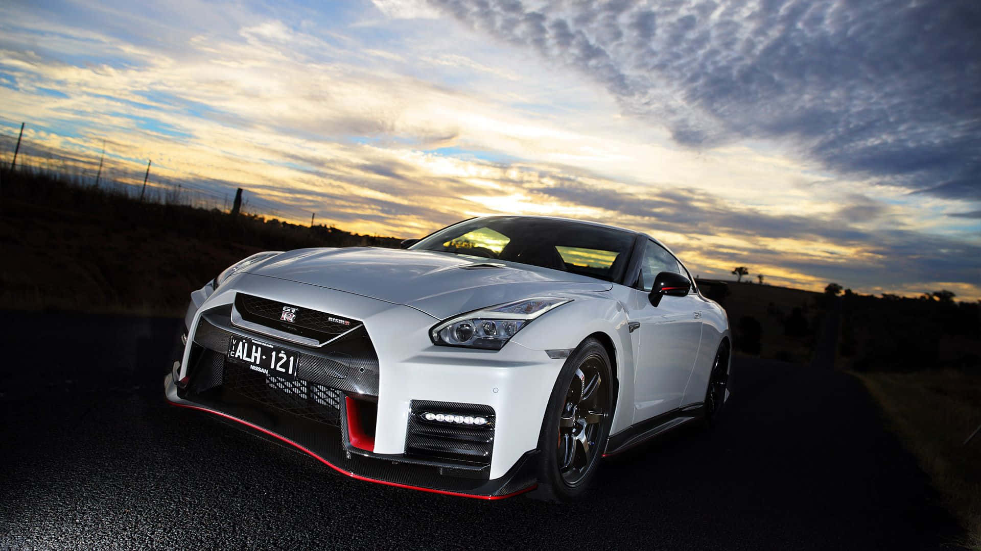 A White Nissan Gtr Parked On A Road Background