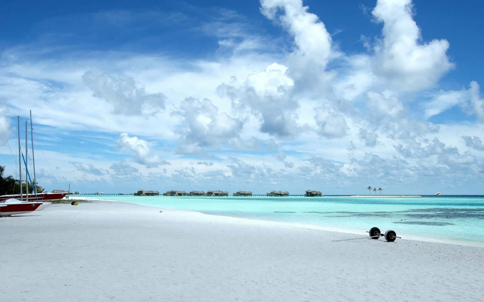 A White Sandy Beach With Boats And Sails Background