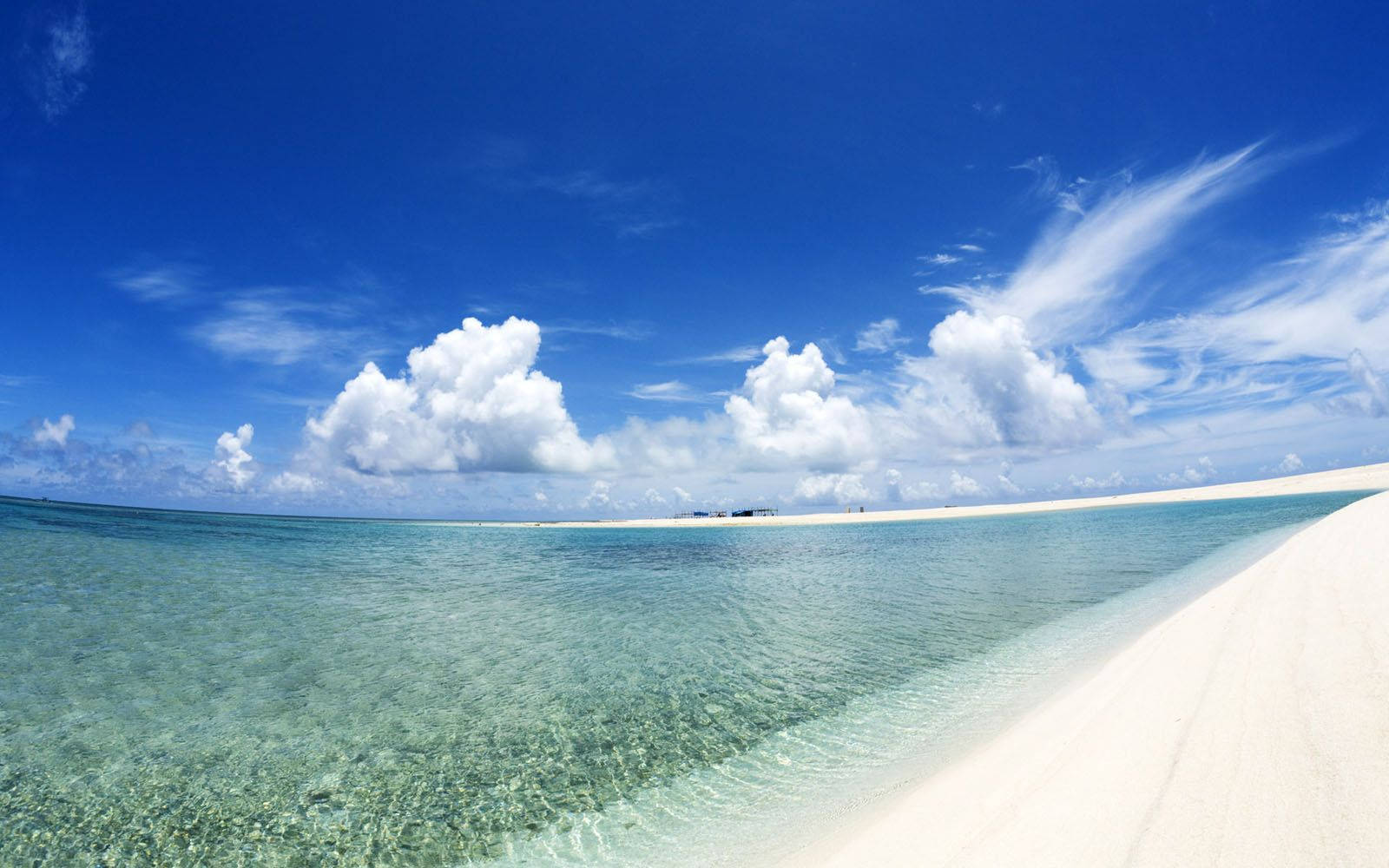 A White Sandy Beach With Clear Water And Clouds Background