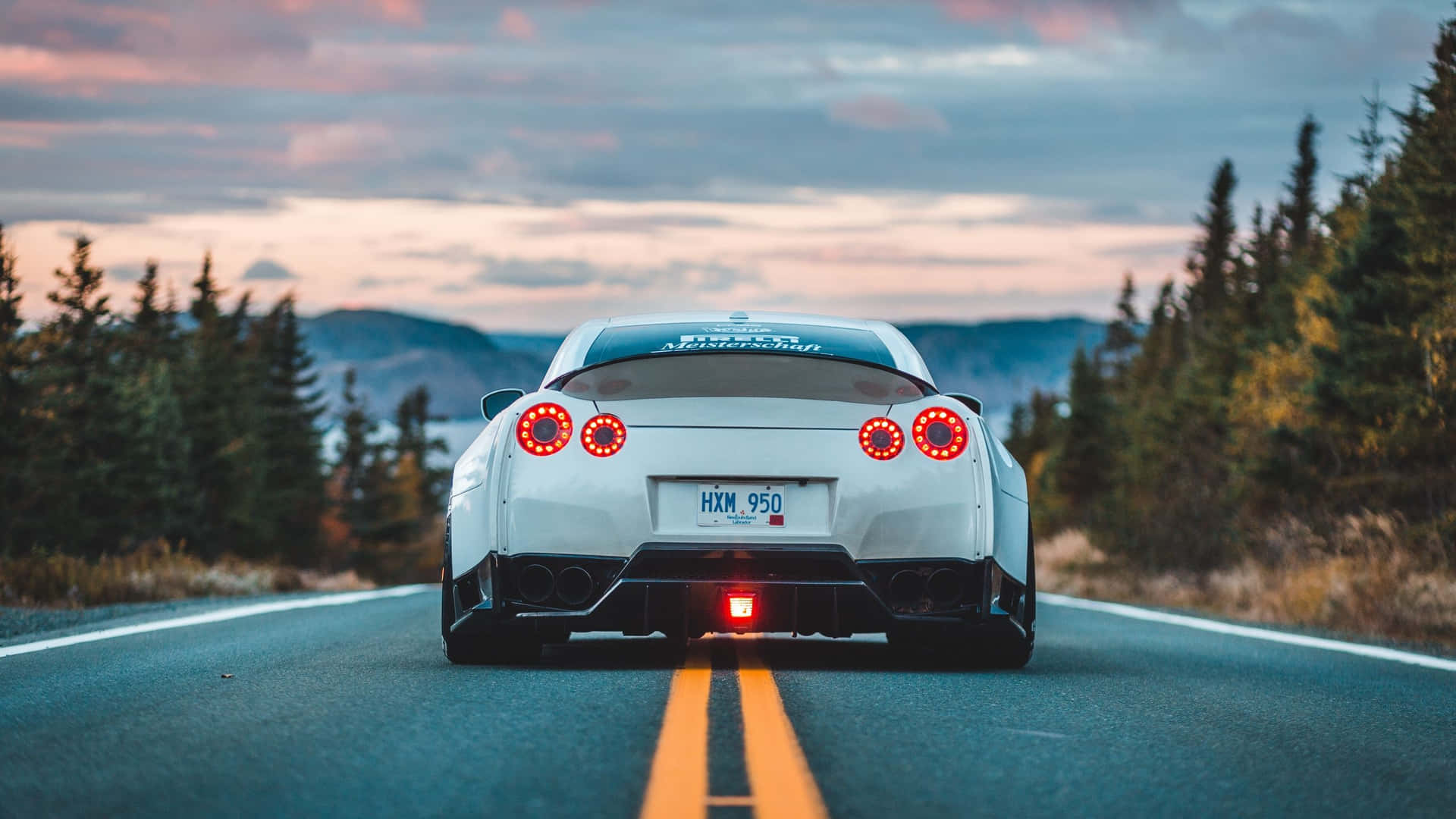 A White Sports Car Driving Down A Road Background