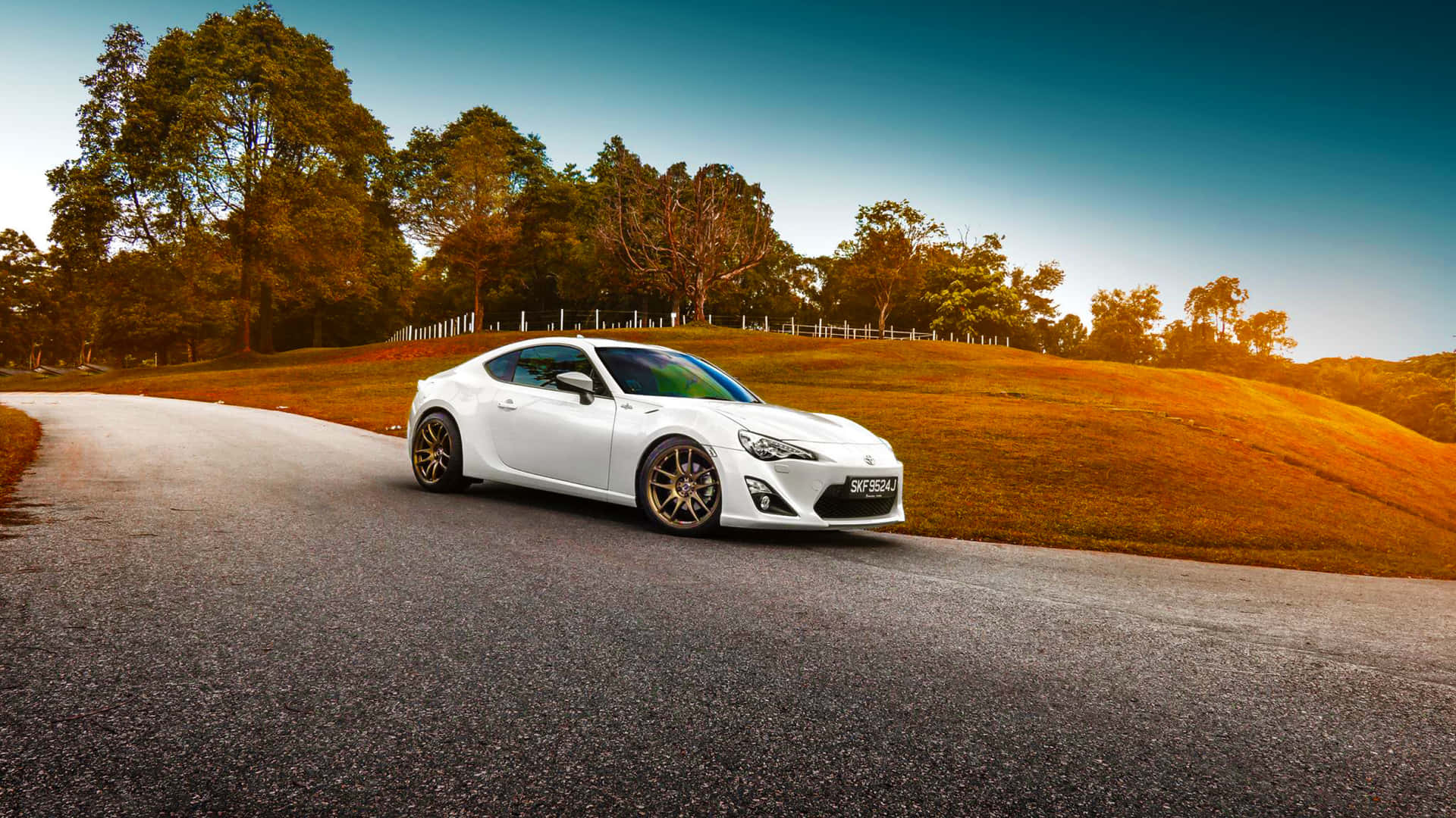 A White Sports Car Driving Down A Road Background