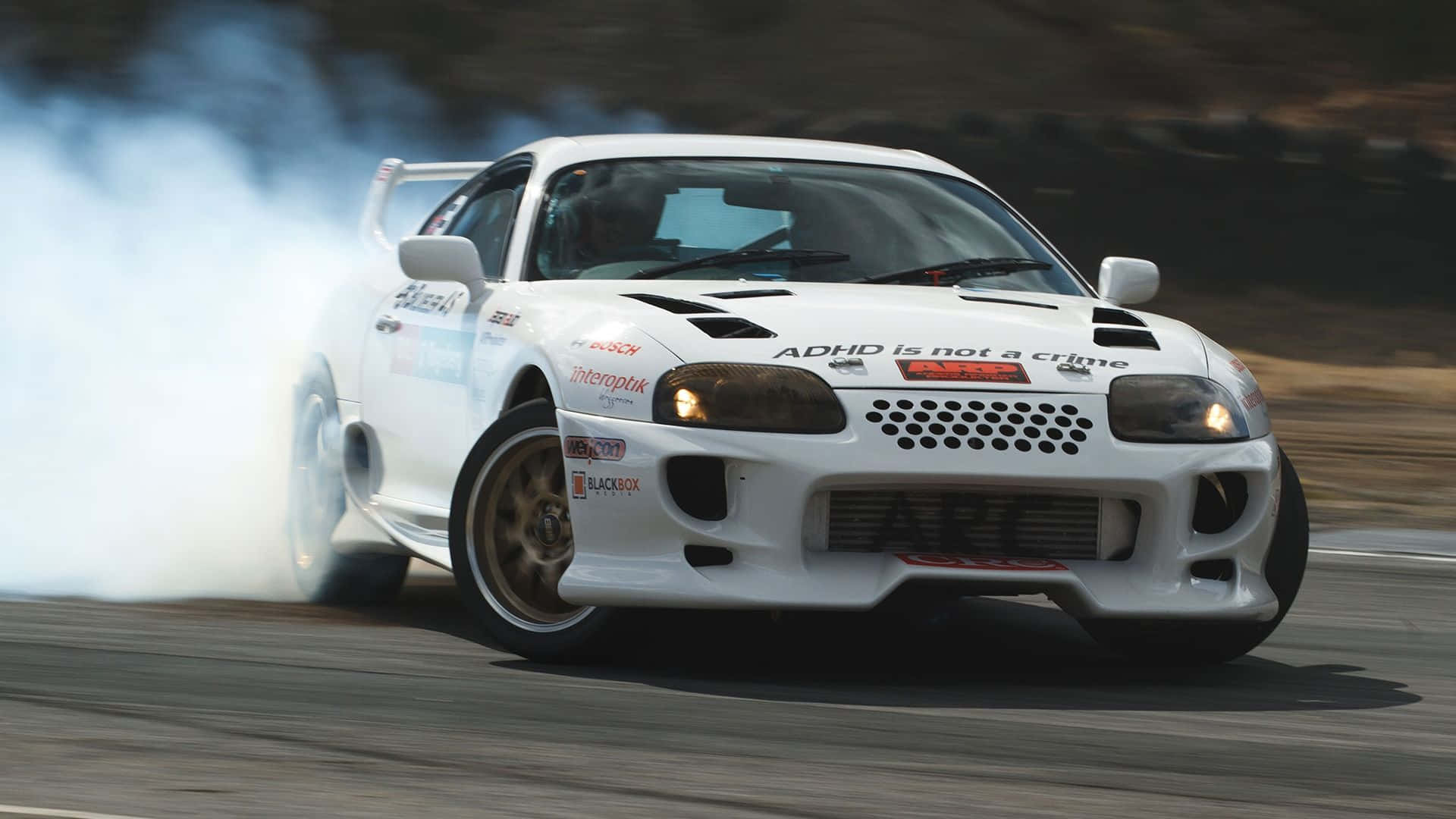 A White Sports Car Is Driving Down A Track With Smoke Coming Out Of It