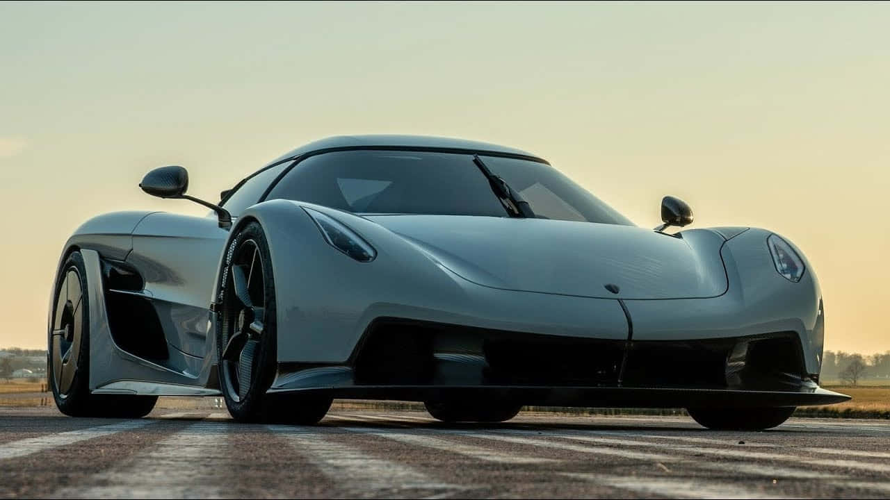 A White Sports Car Is Driving Down The Road