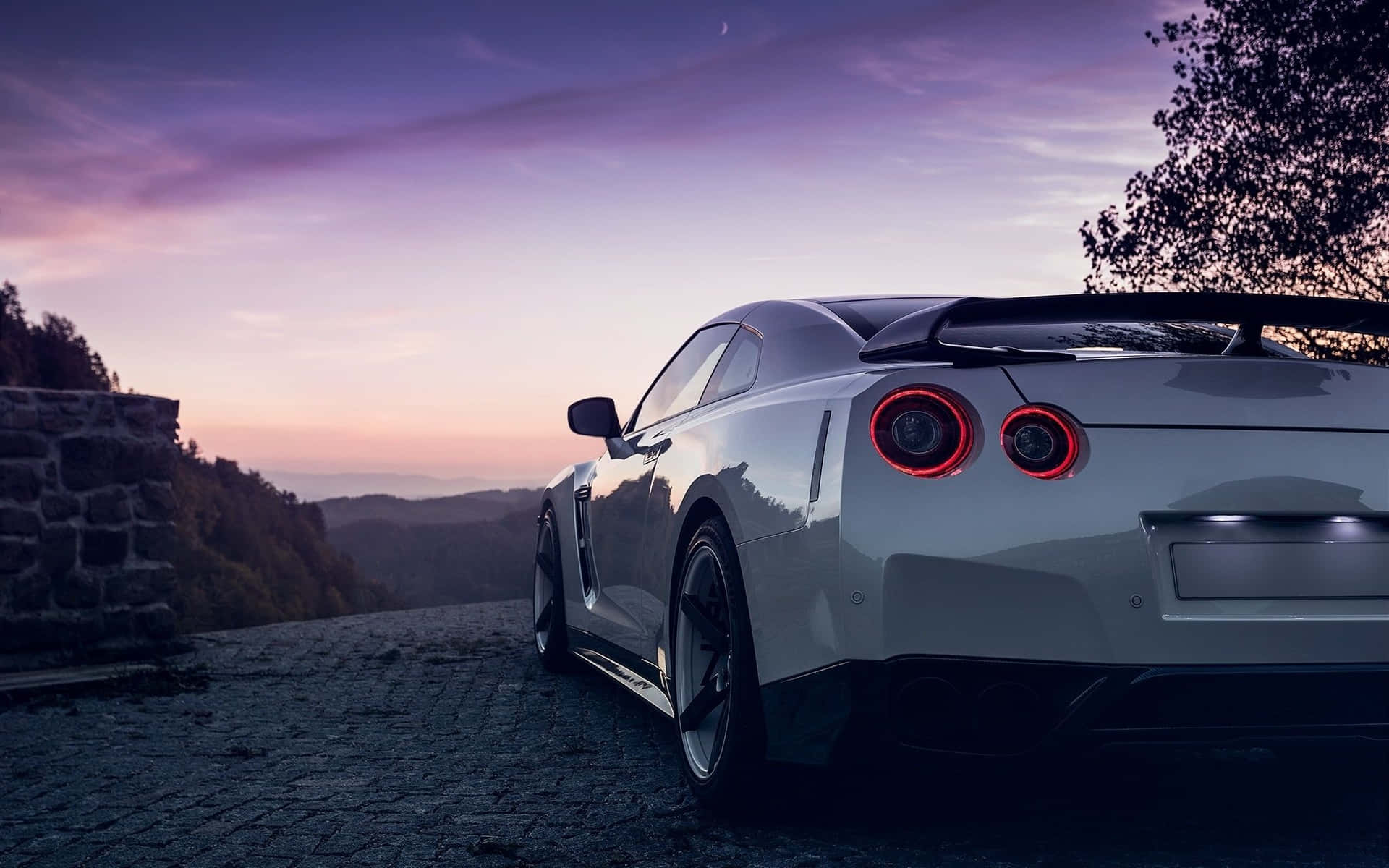 A White Sports Car Parked On A Road At Sunset Background