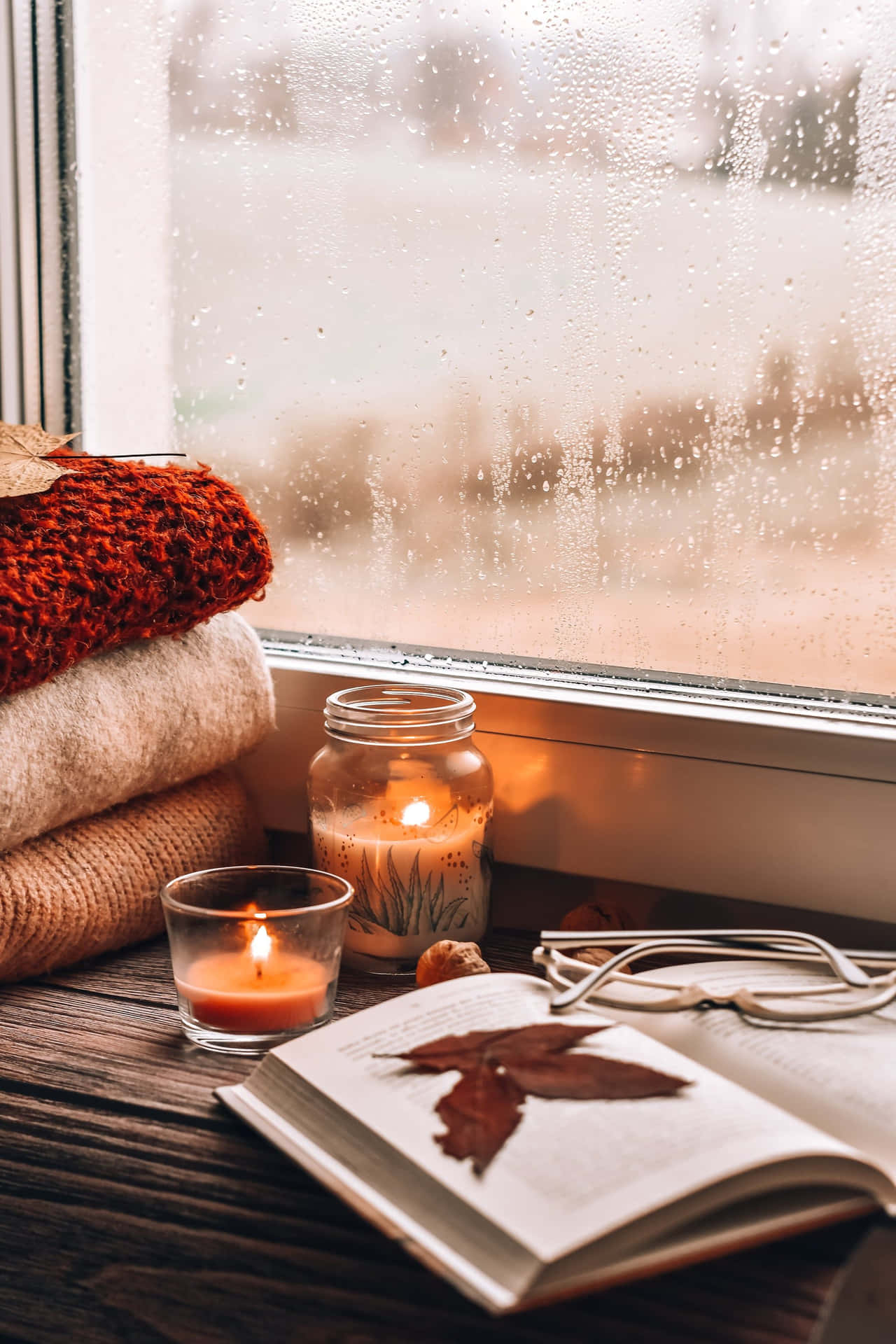 A Window With Candles, A Book, And A Blanket Background