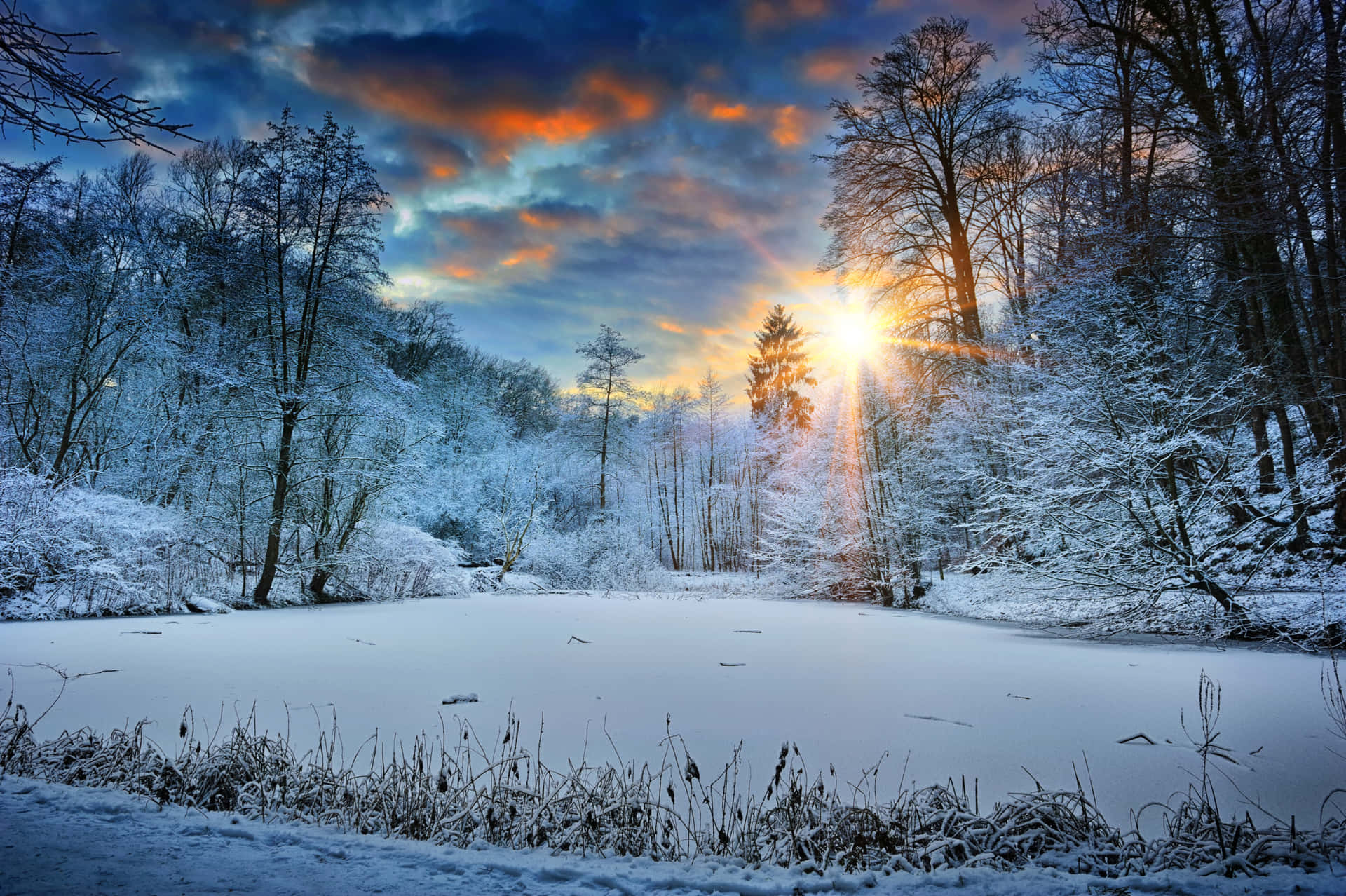 A Winter Sunset Over A Snow Covered Pond Background