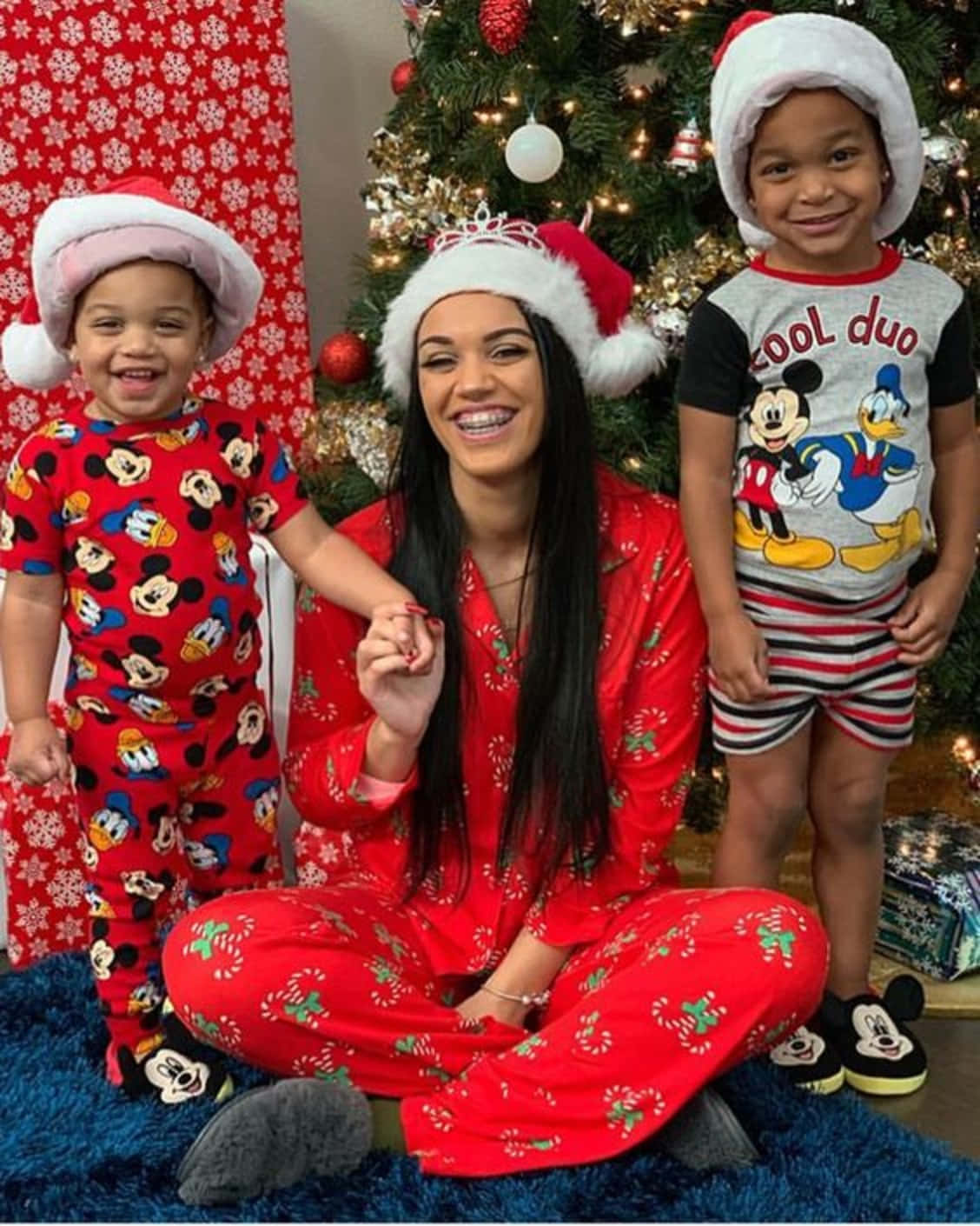 A Woman And Two Children In Christmas Pajamas Background