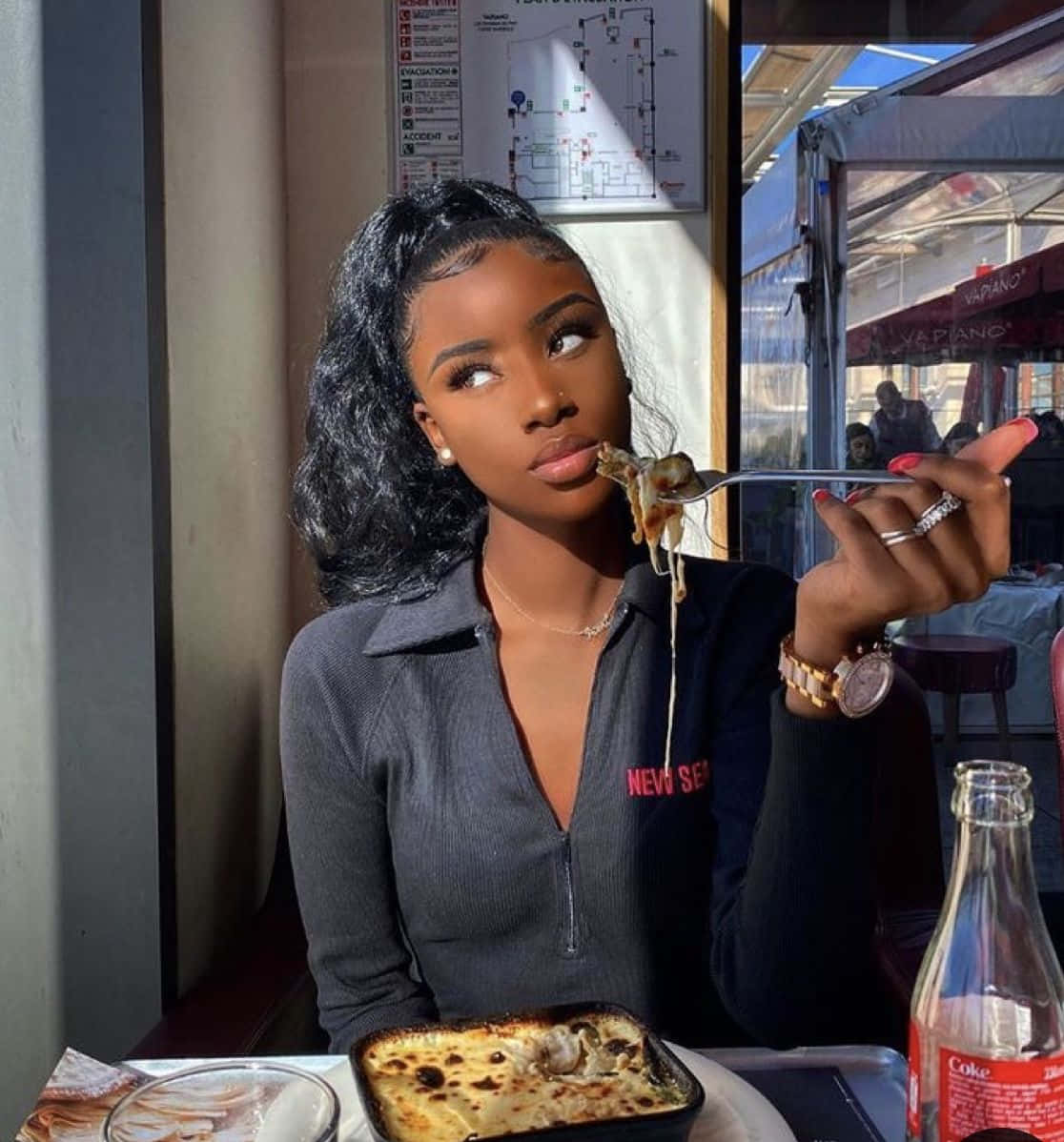 A Woman Eating A Pizza In A Restaurant Background