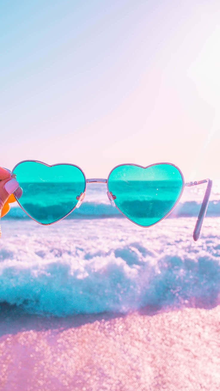 A Woman Holding A Pair Of Sunglasses On The Beach Background