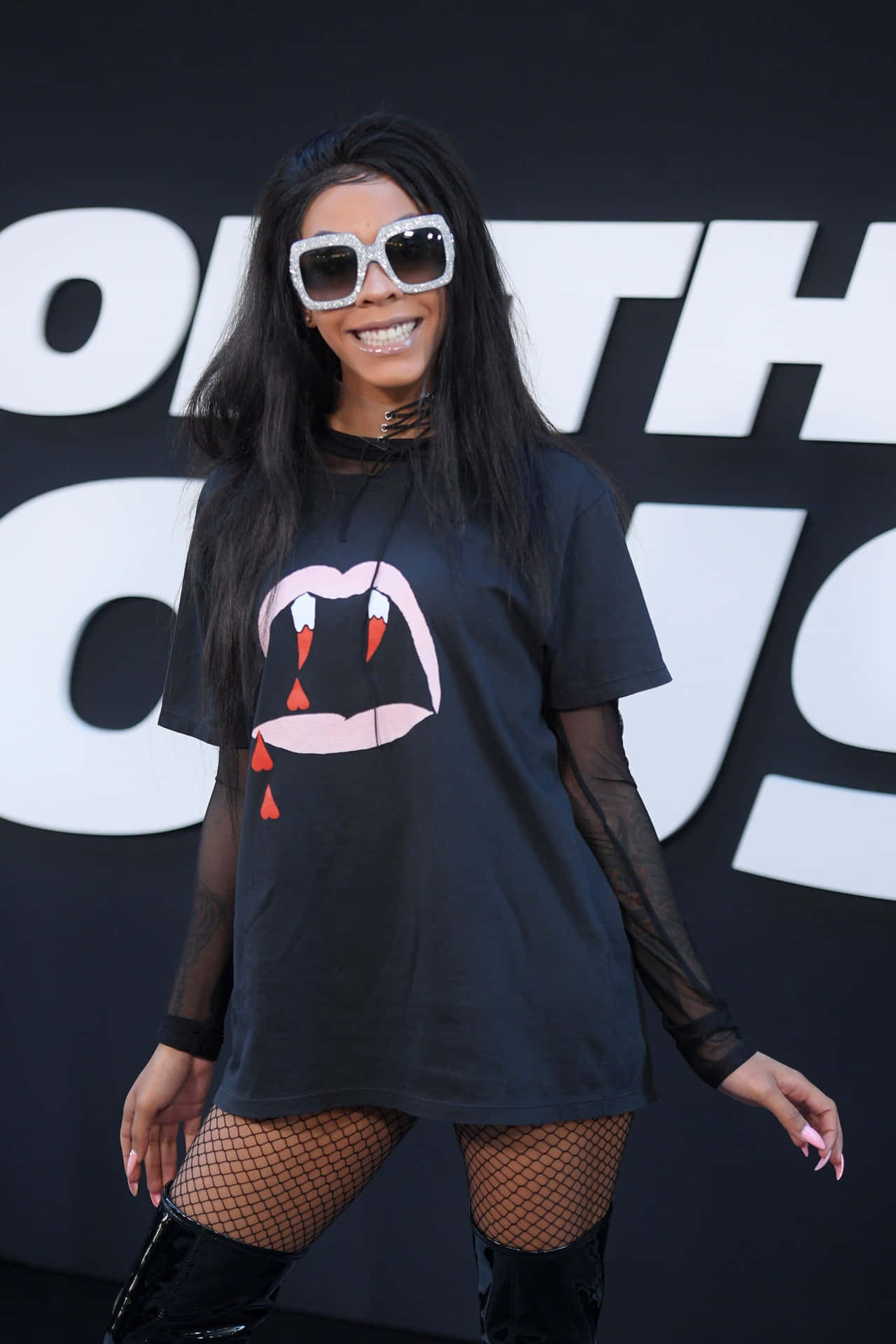 A Woman In A Black Shirt And Thigh High Boots Poses For A Photo Background