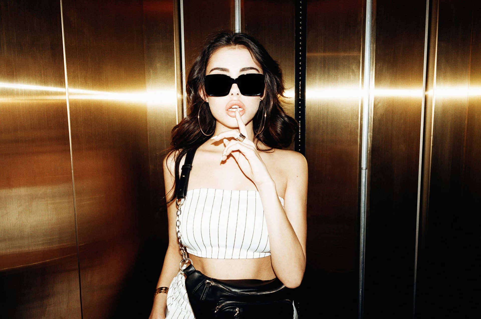 A Woman In A Black Top And Skirt Is Standing In An Elevator Background