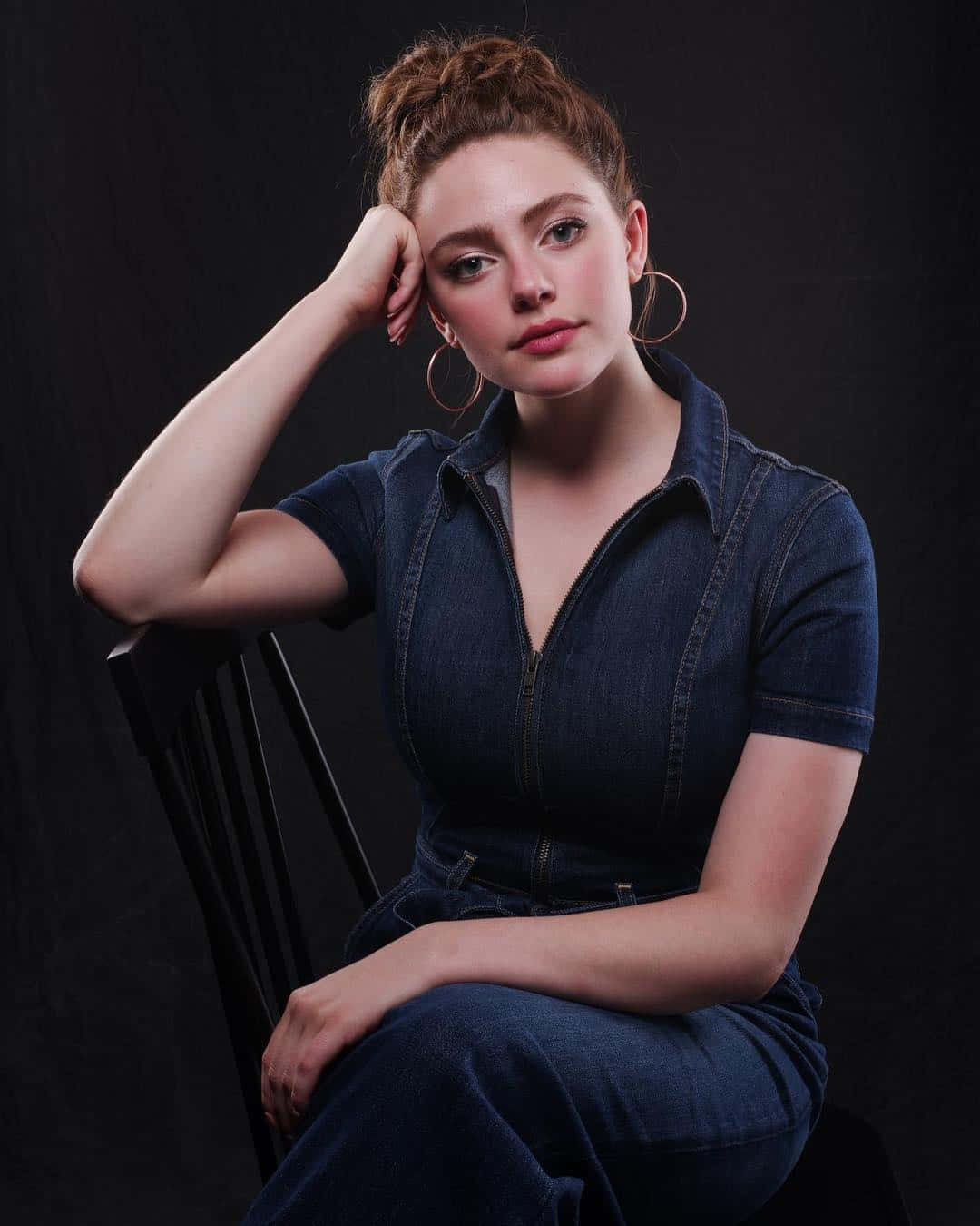 A Woman In A Blue Dress Sitting On A Chair Background