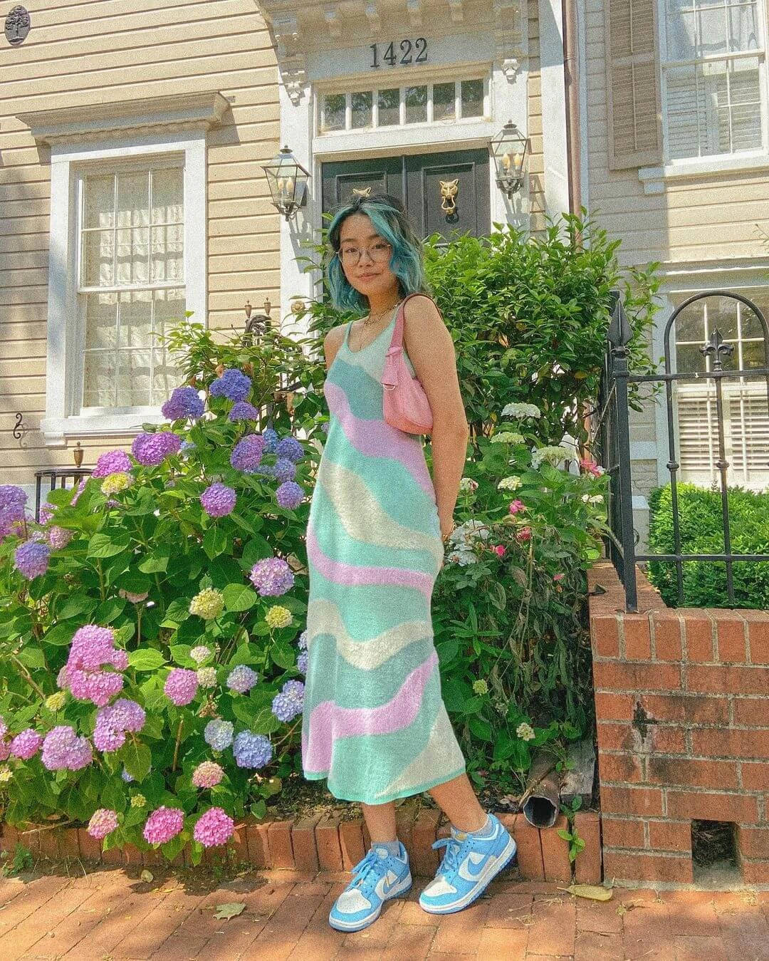 A Woman In A Dress Standing In Front Of A House Background