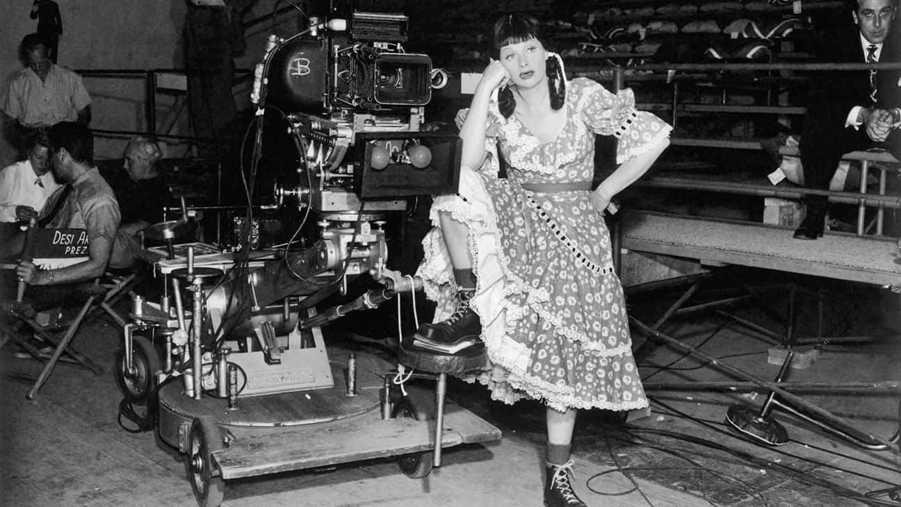 A Woman In A Dress Standing On A Set Background