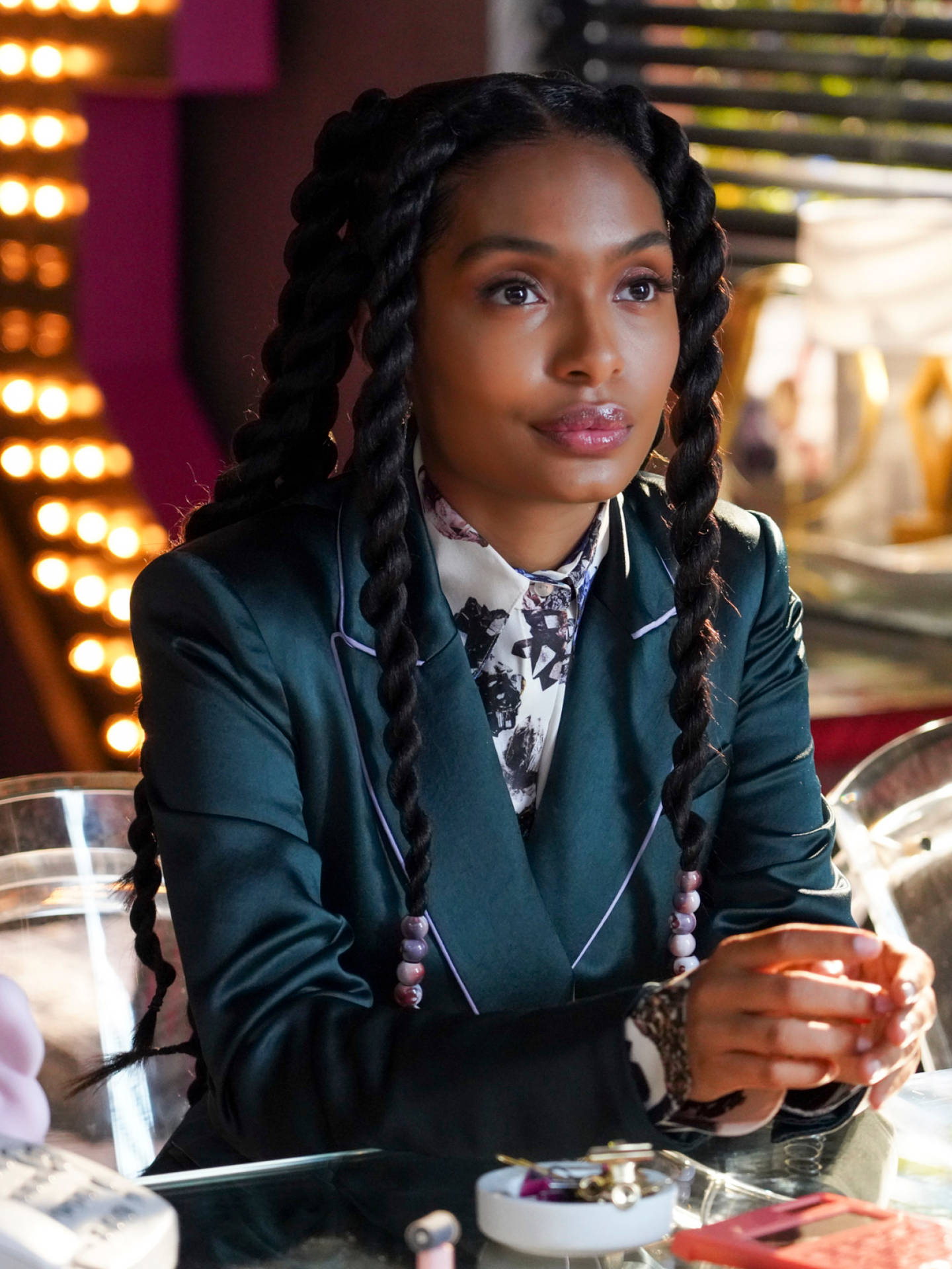 A Woman In A Green Suit Sitting At A Table Background