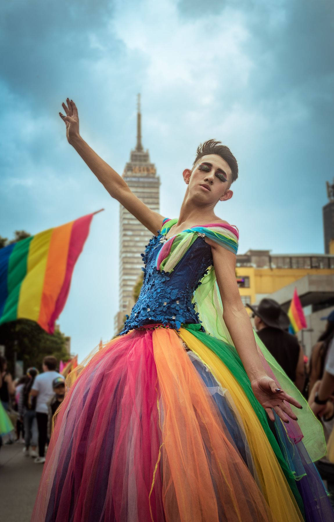 A Woman In A Rainbow Dress Is Holding A Flag