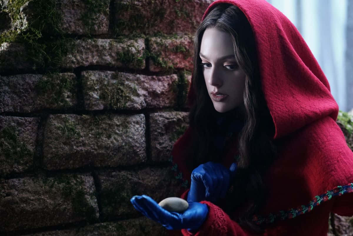 A Woman In A Red Hooded Coat Holding An Egg Background