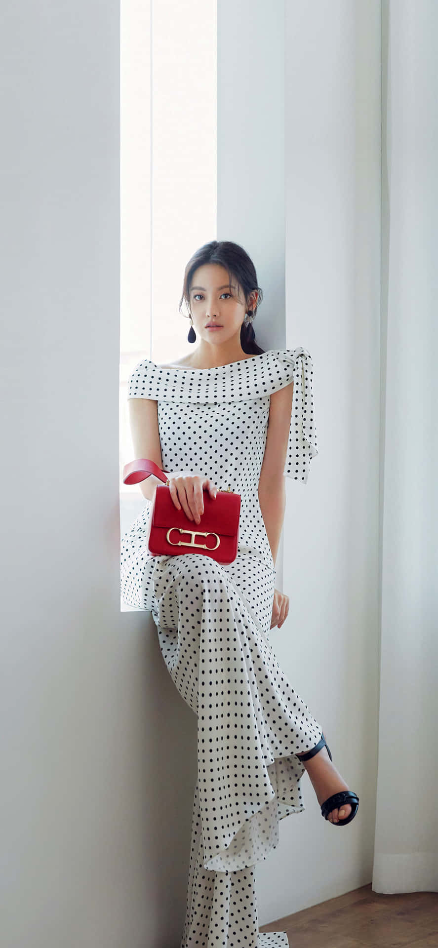 A Woman In A White Dress Leaning Against A Window Background