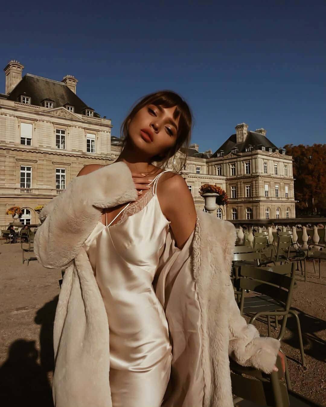 A Woman In A White Dress Posing Outside Background