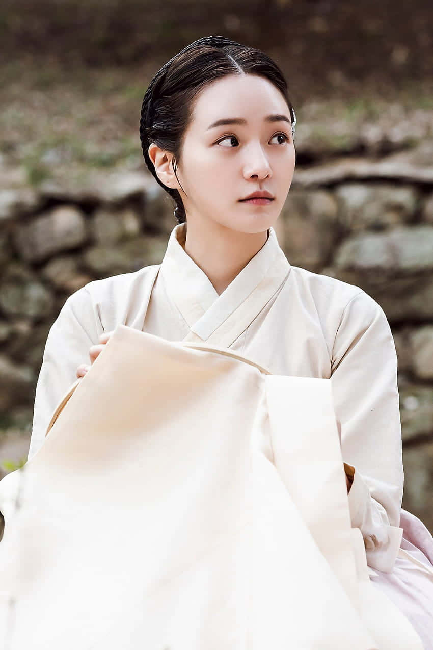 A Woman In A White Kimono Is Sitting On A Stone Background