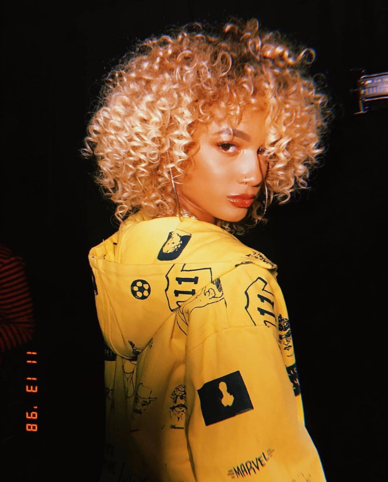 A Woman In A Yellow Jacket With Curly Hair Background