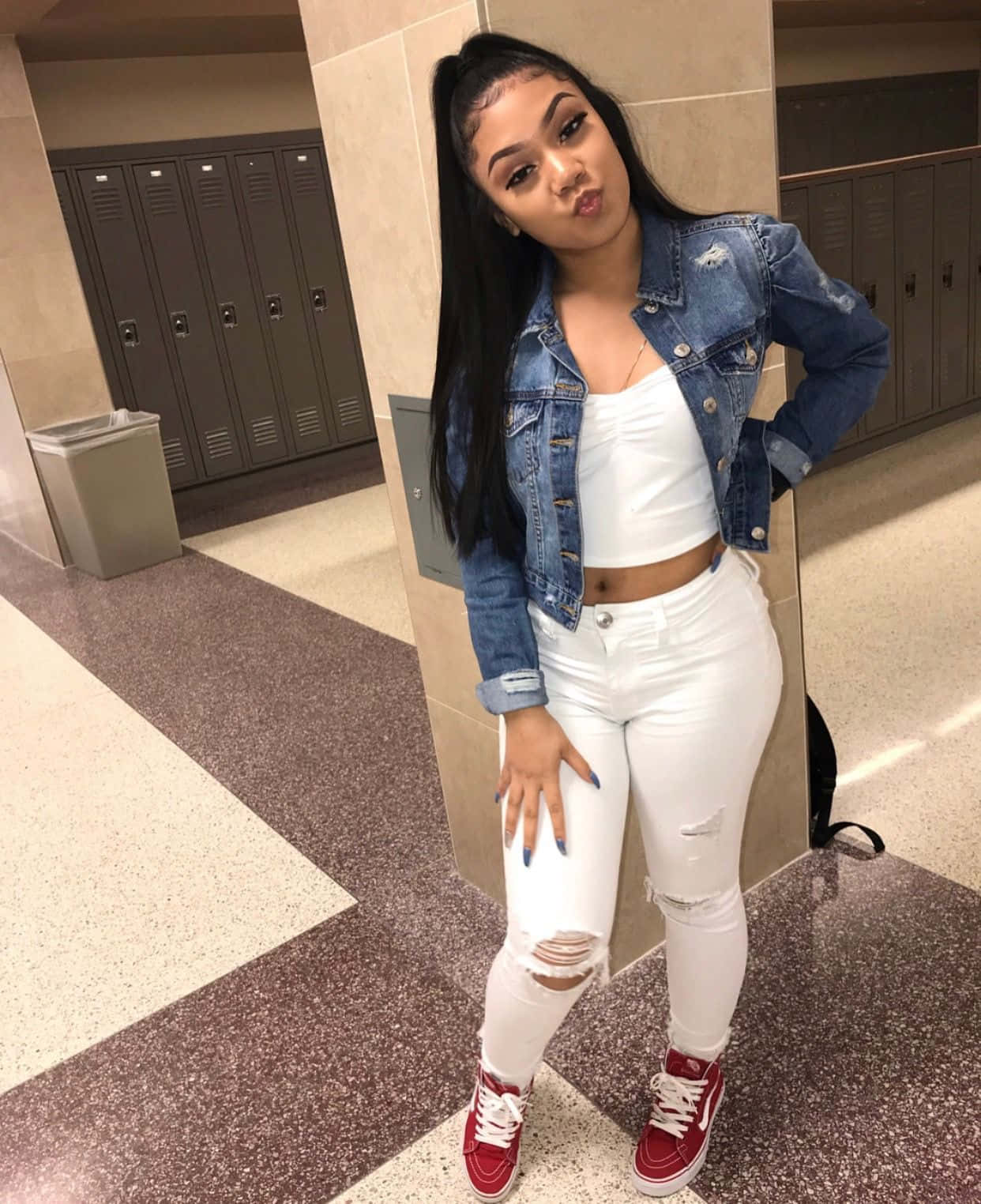 A Woman In White Jeans And Red Sneakers Posing In A Hallway