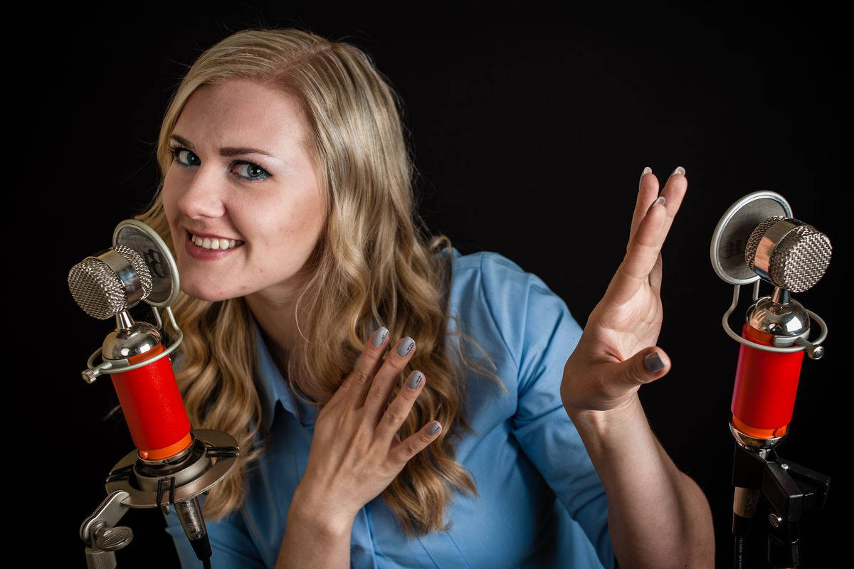 A Woman Is Holding A Microphone And Making A Gesture Background