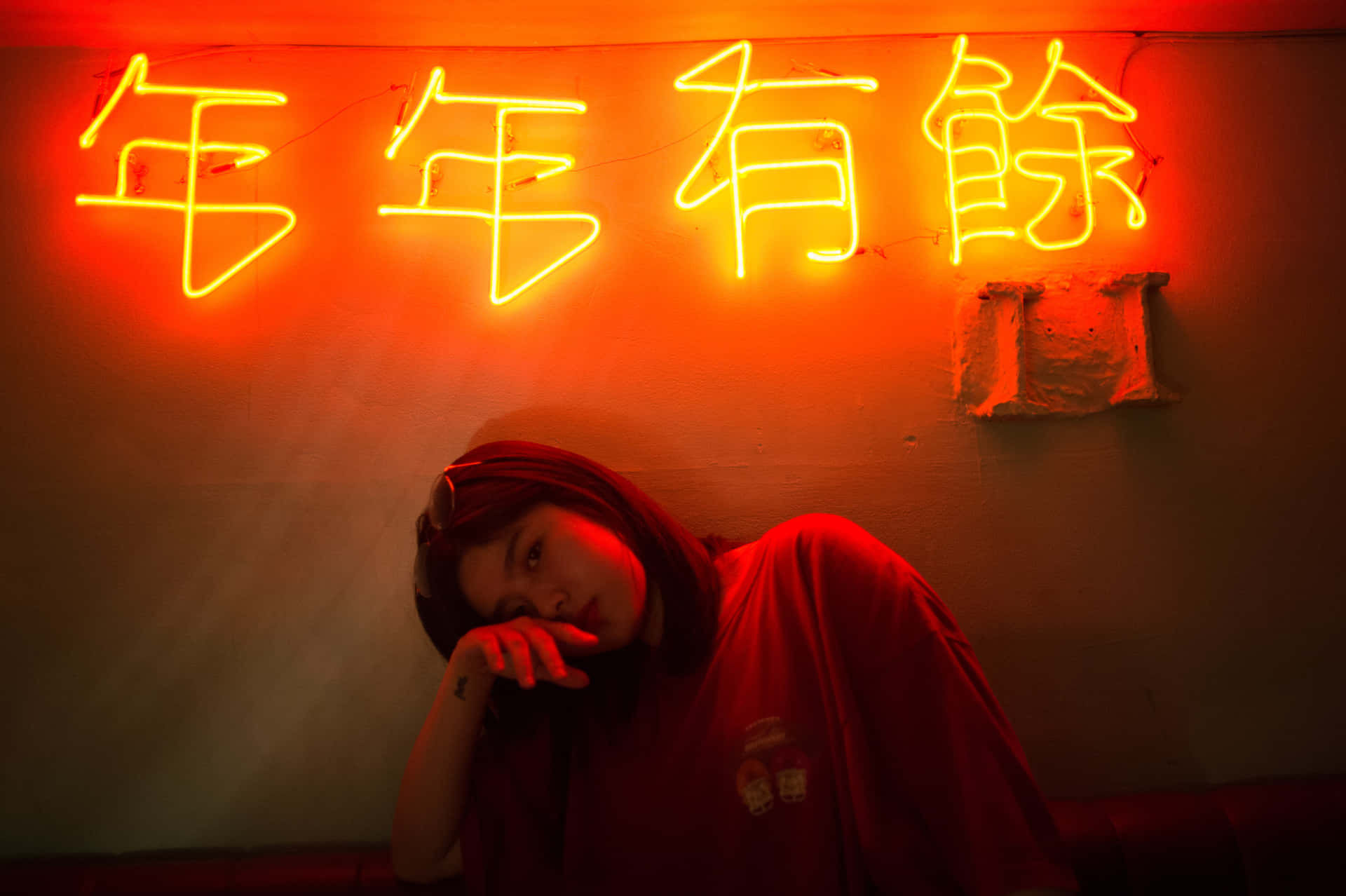 A Woman Is Laying Down In Front Of A Neon Sign